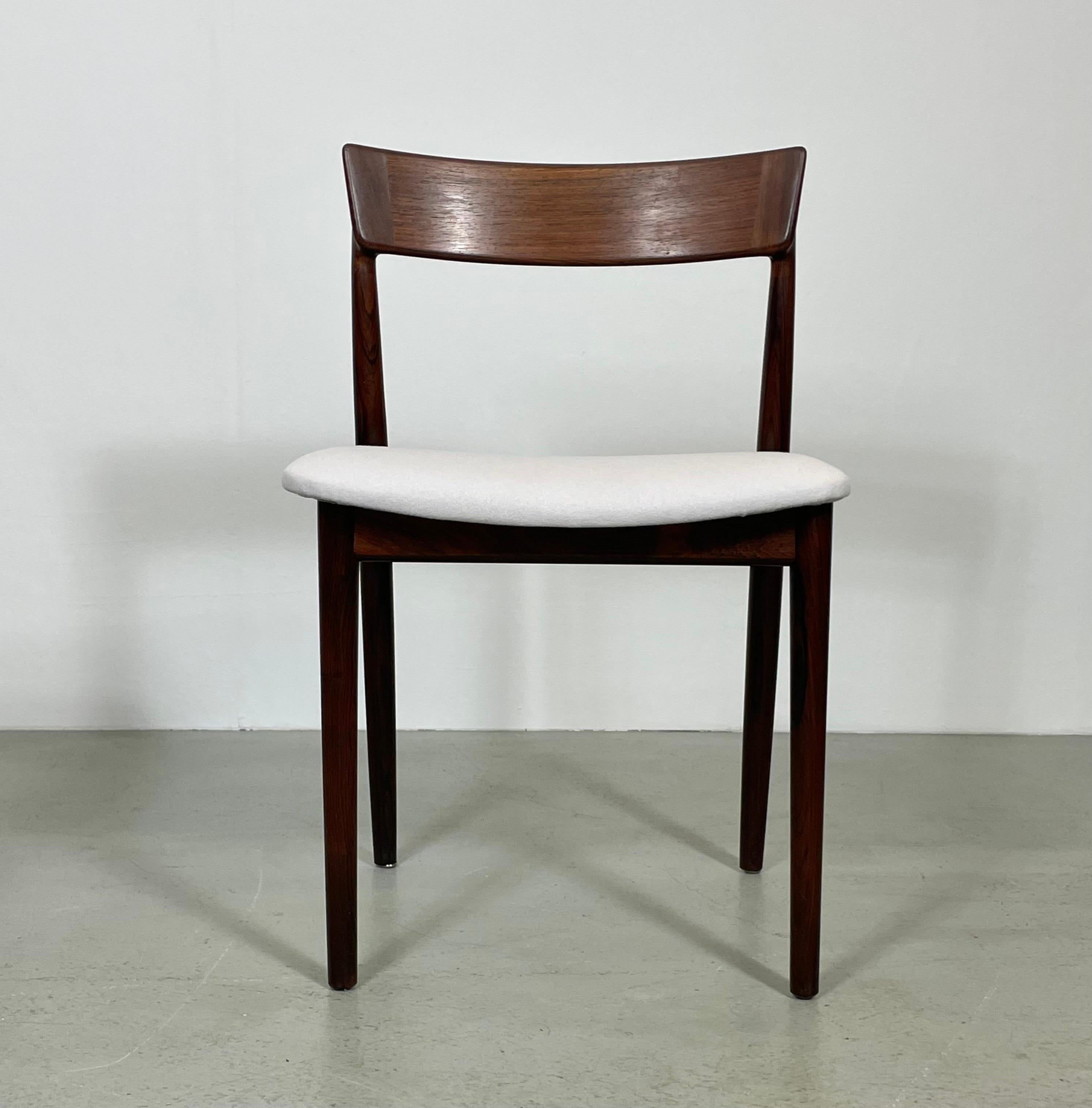 This rare set of 4 chairs was design by Henry Rosengren Hansen for Brande Møbelindustri. It was produced in Denmark in the 1960s. The dining chairs are made of solid rosewood the seat has been restored and feature an elegant cover im light-grey wool