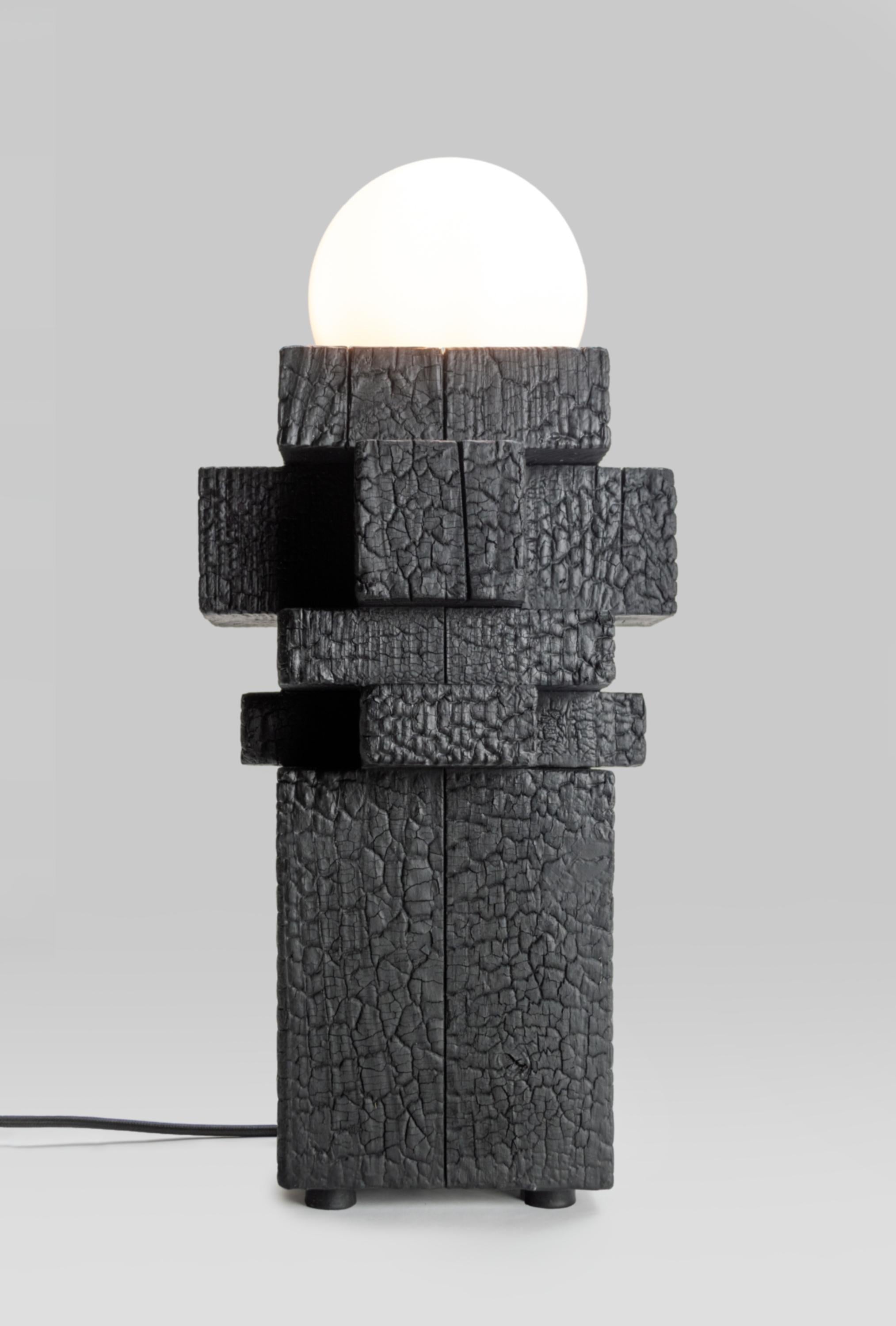 Audacieuse, sculpturale et élémentaire, la lampe 4X est un jeu saisissant de matériaux bruts et de design raffiné. Fabriquée à partir de blocs de bois massif, cette lampe transforme une texture marquée par les flammes en une déclaration