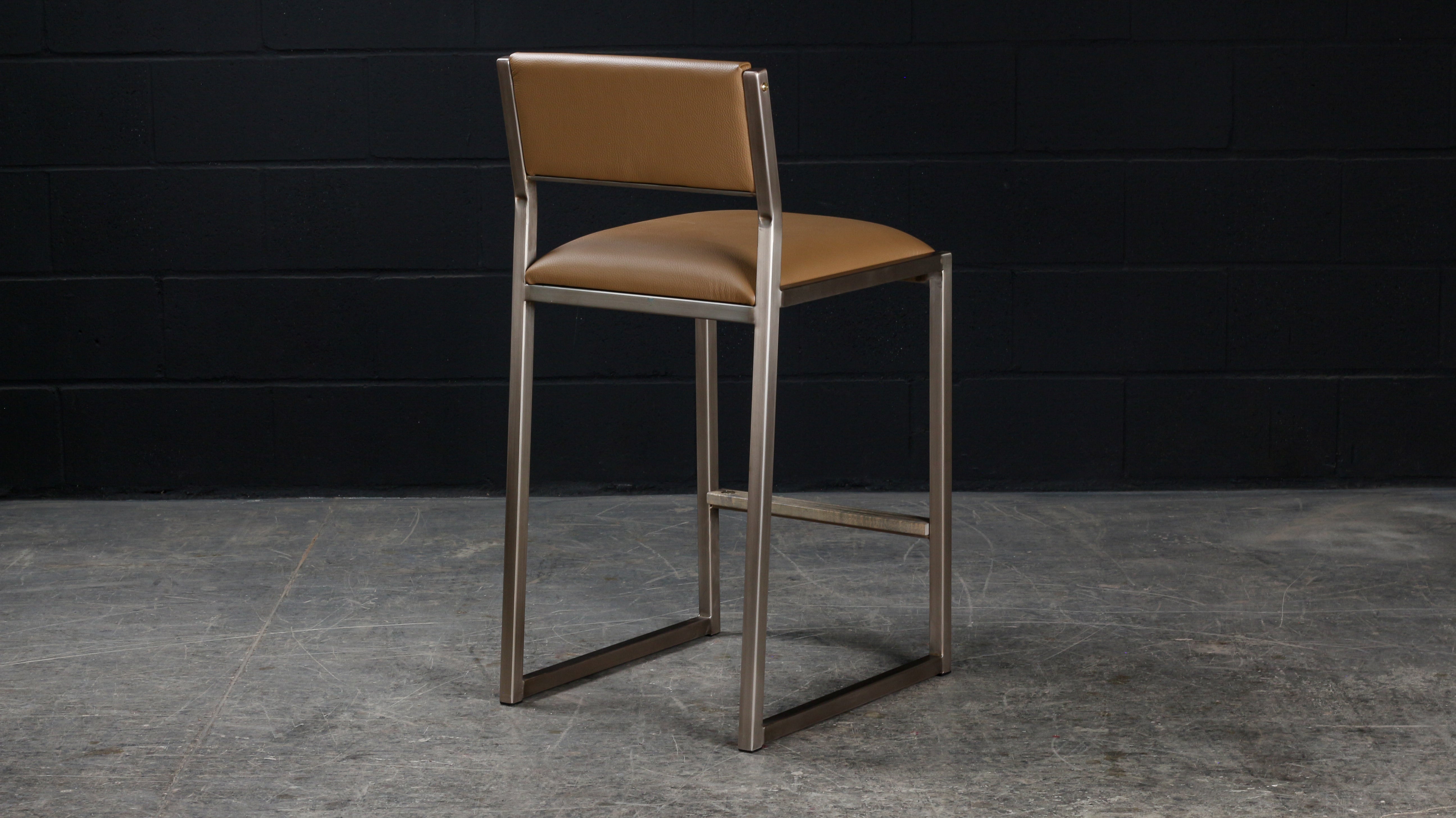 The shaker modern counter stool chair is handmade to order. Featuring our optional Luxurious Dull Champagne metal frame and a Genuine leather seat and back. Also offered in COM or COL. Inspired by the boarding ladder steps of an old boat. The