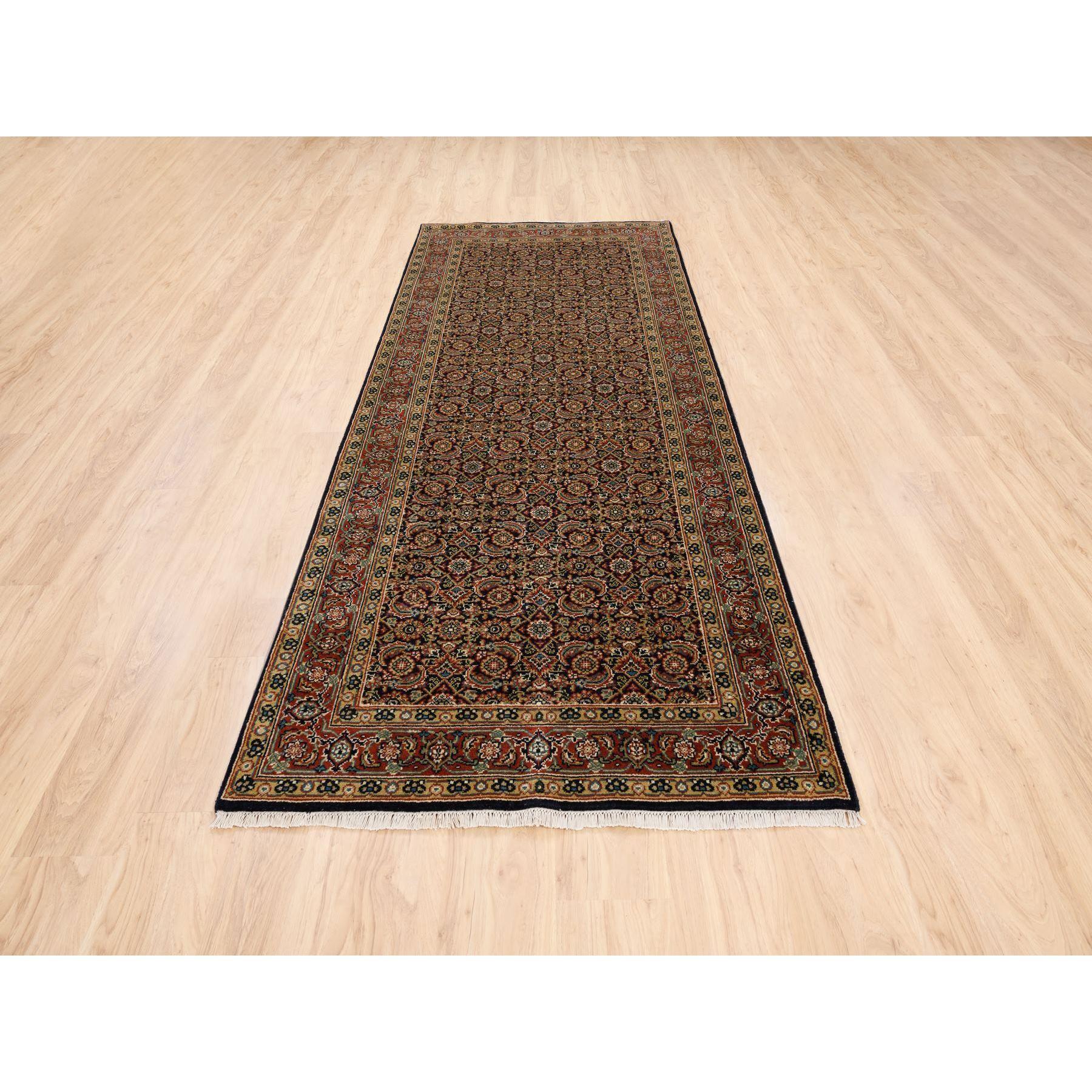 Se trata de una auténtica alfombra Herati de color negro azabache con diseño de peces en tejido denso de lana 175 KPSI anudada a mano y tamaño de galería oriental. Se ha anudado durante meses y meses en la artesanía centenaria del tejido