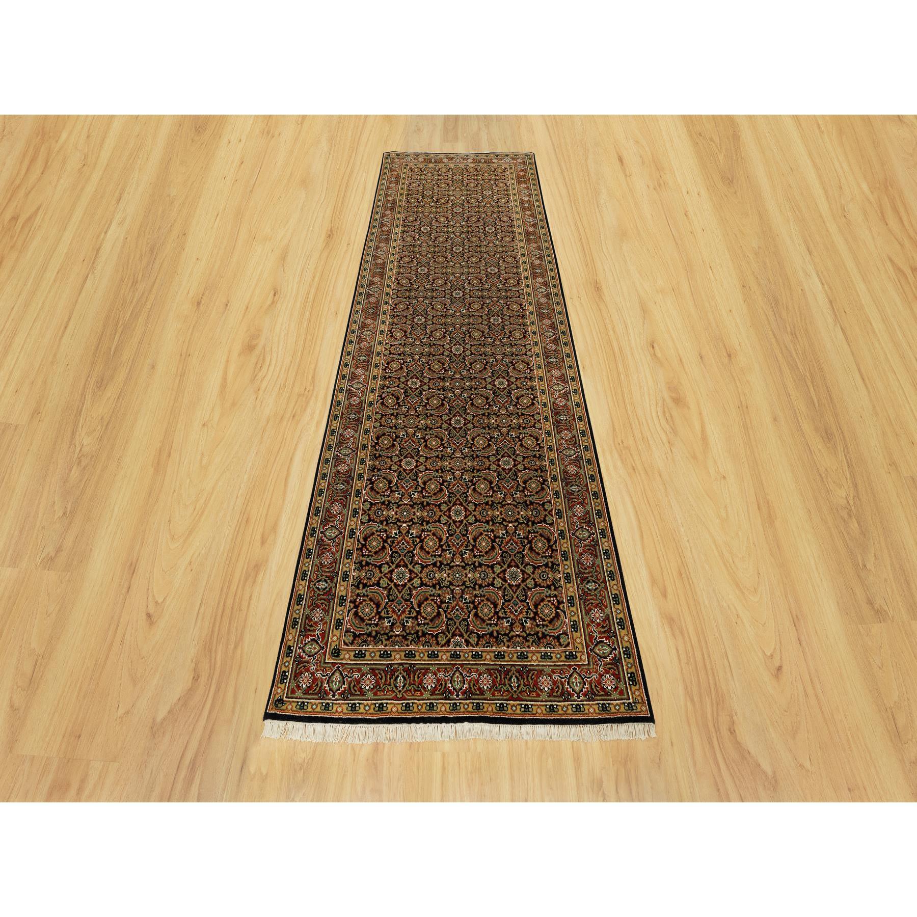 Il s'agit d'un véritable tapis oriental noué à la main en laine épaisse et pelucheuse, de couleur noir de jais et orné d'un motif de poisson. Il a été noué pendant des mois et des mois selon des techniques de tissage séculaires par des artisans