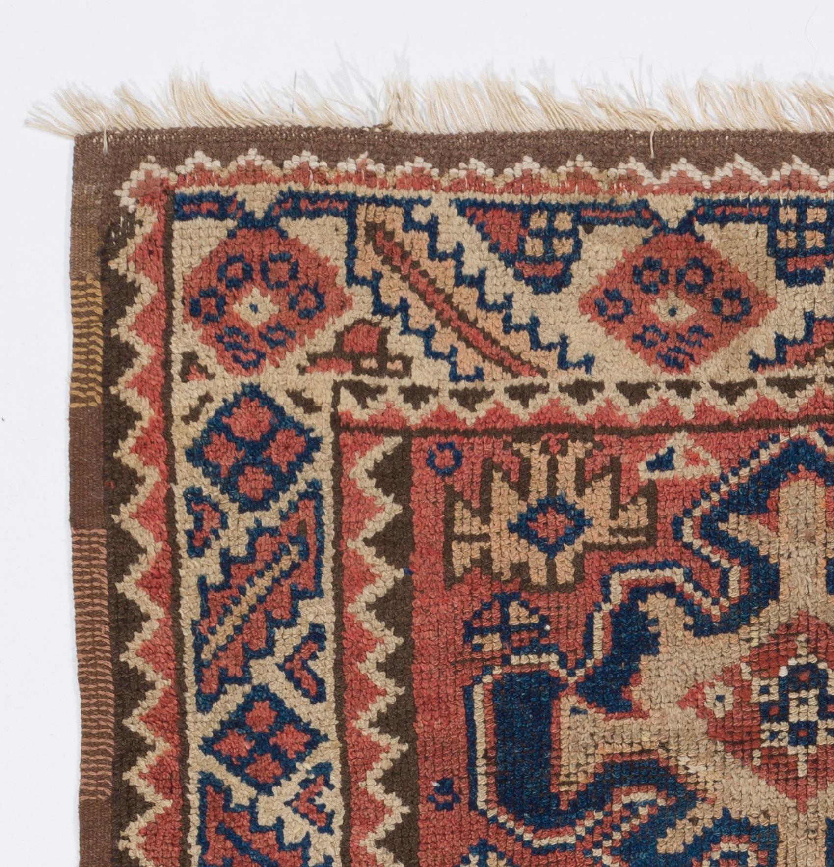 A hand-knotted vintage rug made in the 1940s from Eastern Turkey featuring a  design of three linked slightly curvilinear latch-hook medallions in terra-cotta red, dark indigo and beige against a terra-red field and a border decorated with geometric