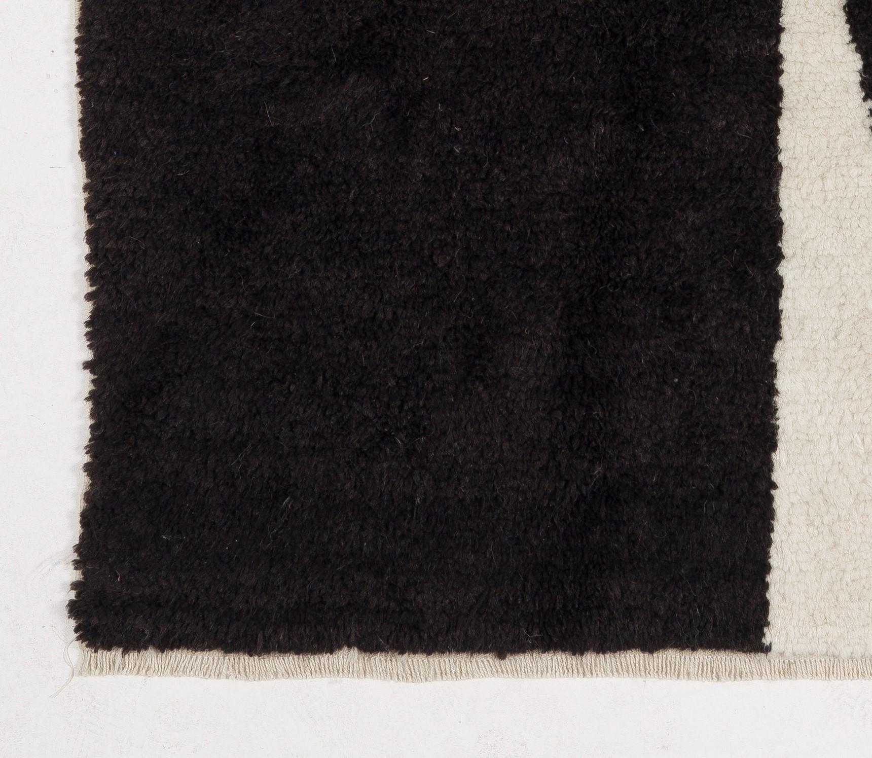 Ce tapis marocain exquis, noué à la main à partir de laine de mouton finement filée à la main, présente un motif géométrique audacieux dans un magnifique bleu indigo et noir vif sur un fond crème. Un véritable objet de référence qui peut facilement