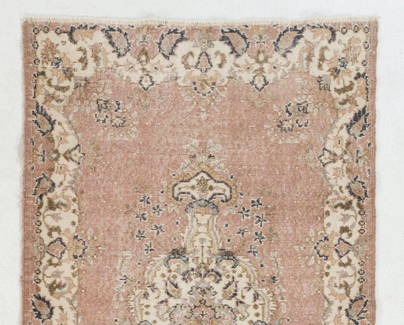 A vintage hand-knotted accent rug from Turkey made in the 1960s with wool pile on cotton foundation. It features a lovely floral-themed design with a central medallion and a curvilinear border, both decorated intricately with lush floral heads,