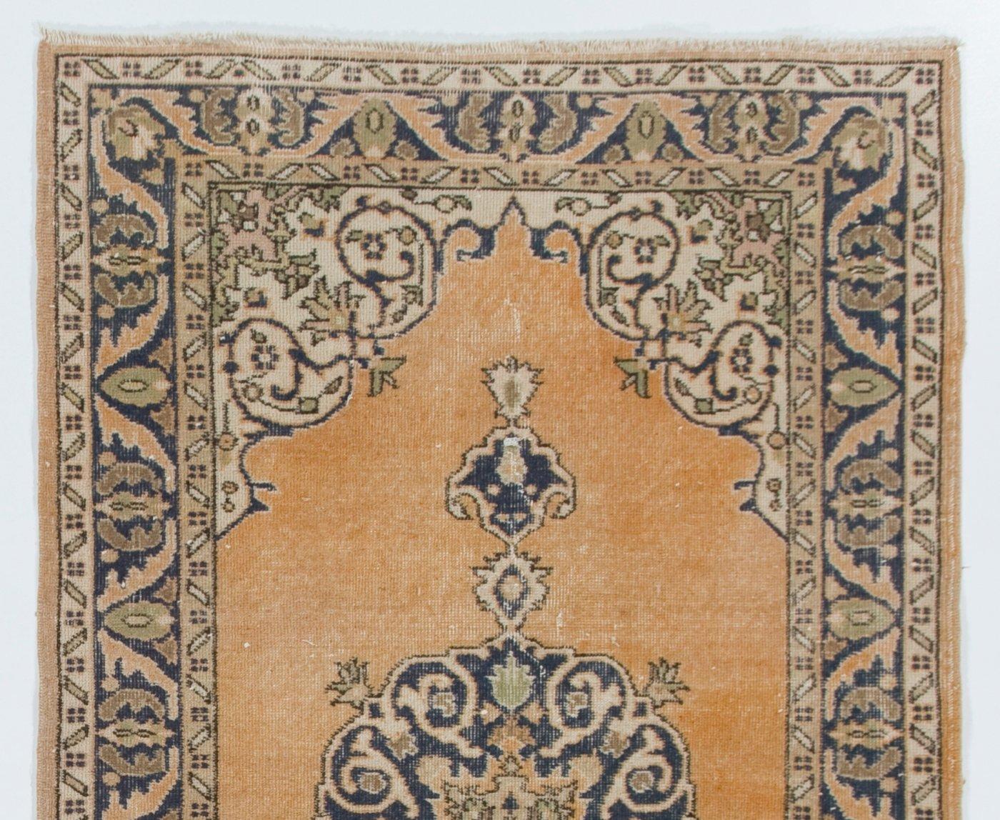 A vintage rug from Central Turkey, finely hand-knotted with even medium wool pile on cotton foundation. It features a classical medallion design in indigo against a soft orange field framed by arabesque corner pieces in beige and a border filled