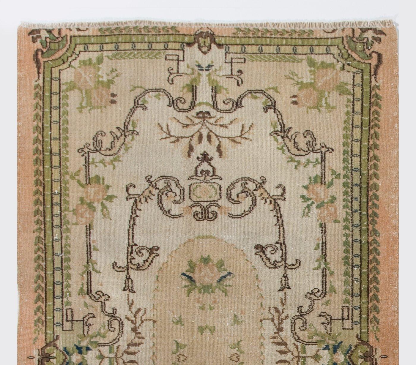 A vintage Turkish rug inspired by French-Aubusson style rugs with a design of romantic cabbage roses in large nested cartouches in ivory, beige, salmon pink and moss green. The rug was hand-knotted in the 1960s and it has medium wool pile on cotton