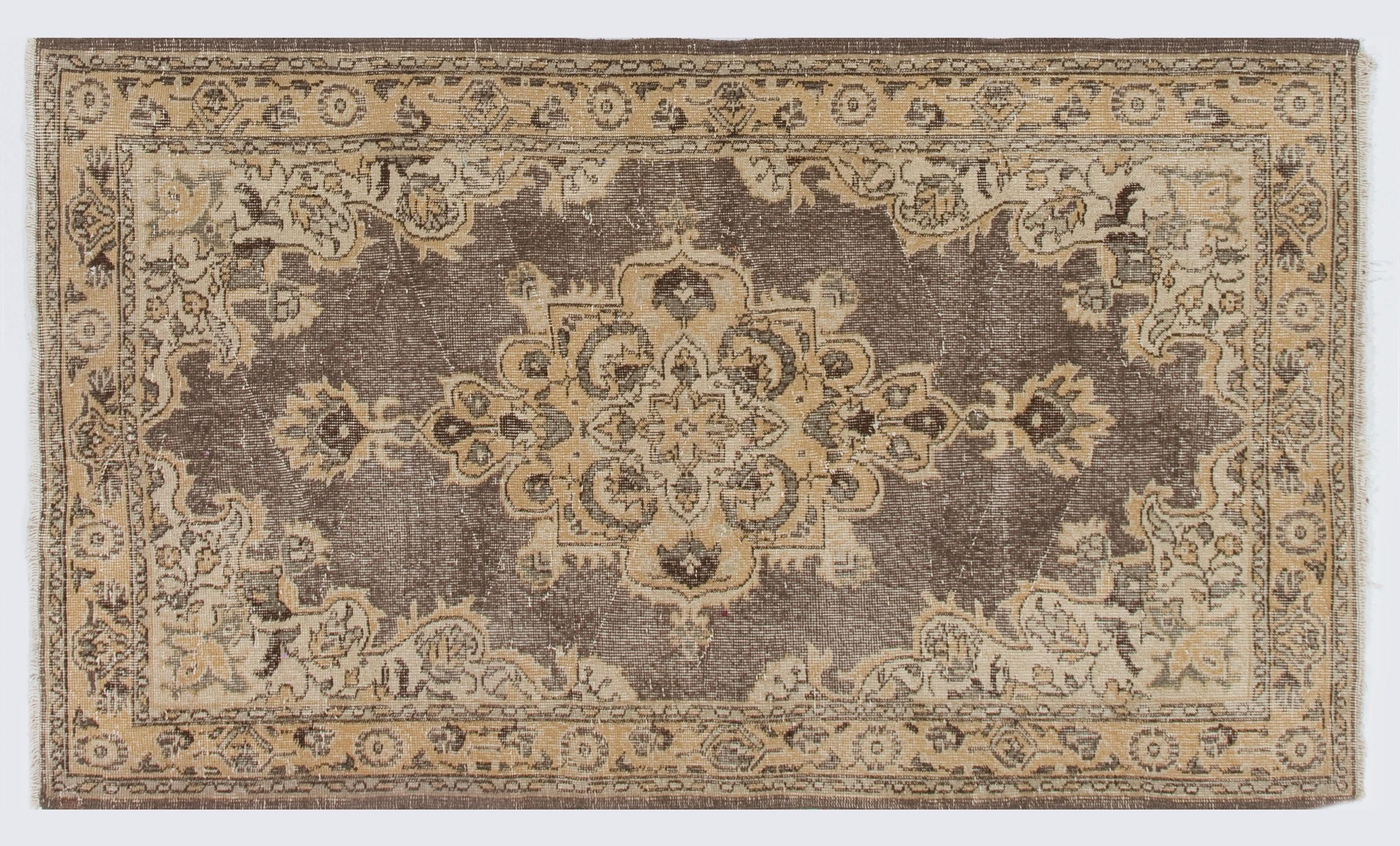 A vintage hand-knotted accent rug that was hand-knotted in the 1960s in Turkey, featuring a medallion design in earthy colors of beige, sand and brown. The rug has distressed low wool pile on cotton foundation, which gives it an antiquated look. It