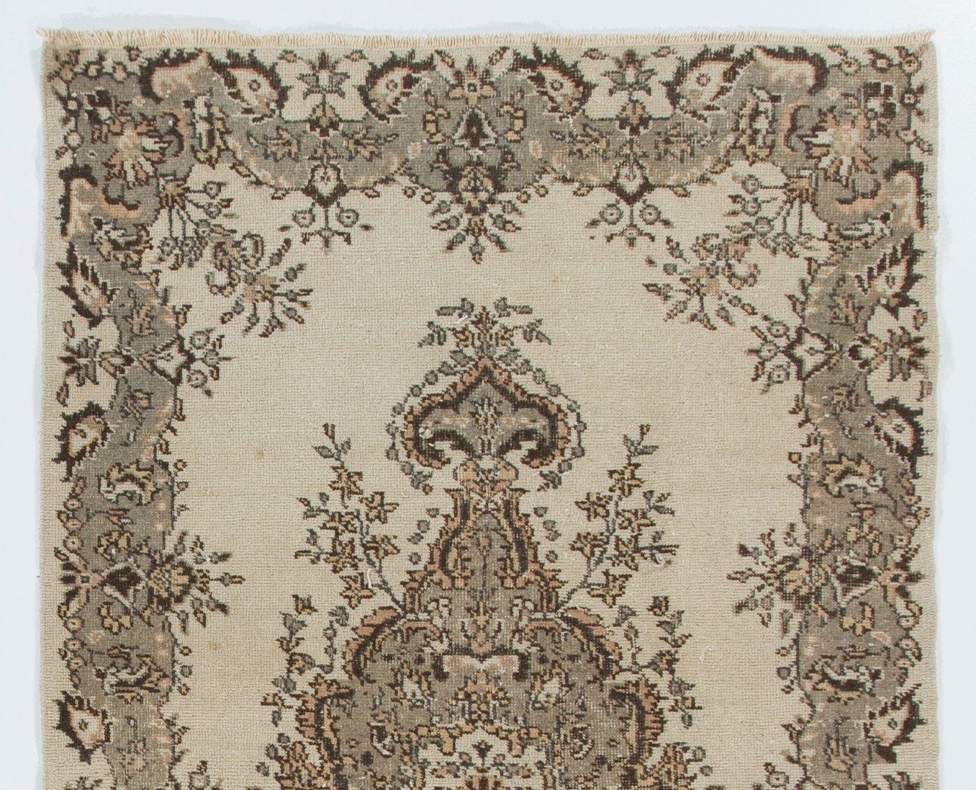 This handmade vintage Central Turkish rug features a floral medallion framed by flowing, floral borders in gray, cream and touches of peach. It was hand-knotted in the 1960s with low wool pile on cotton foundation. The rug is in very good condition,