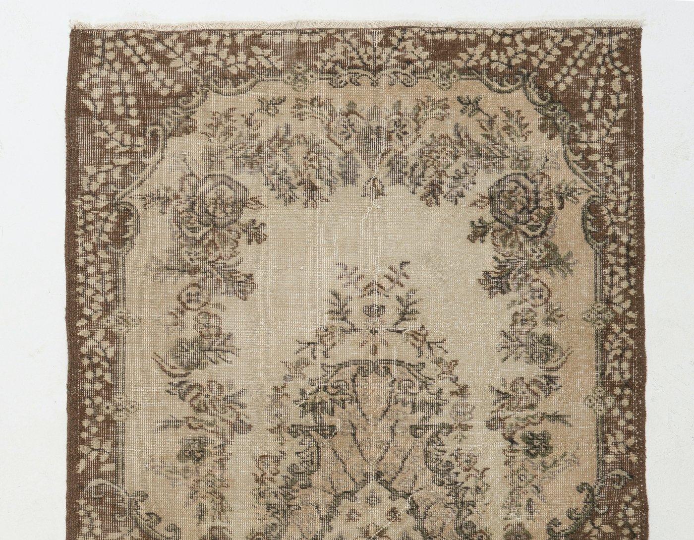 This is a hand-knotted vintage Turkish accent rug. The rug features a floral medallion design in a field decorated with floral motifs. It has low distressed wool pile on cotton foundation, is in very good condition, sturdy and clean as a brand new