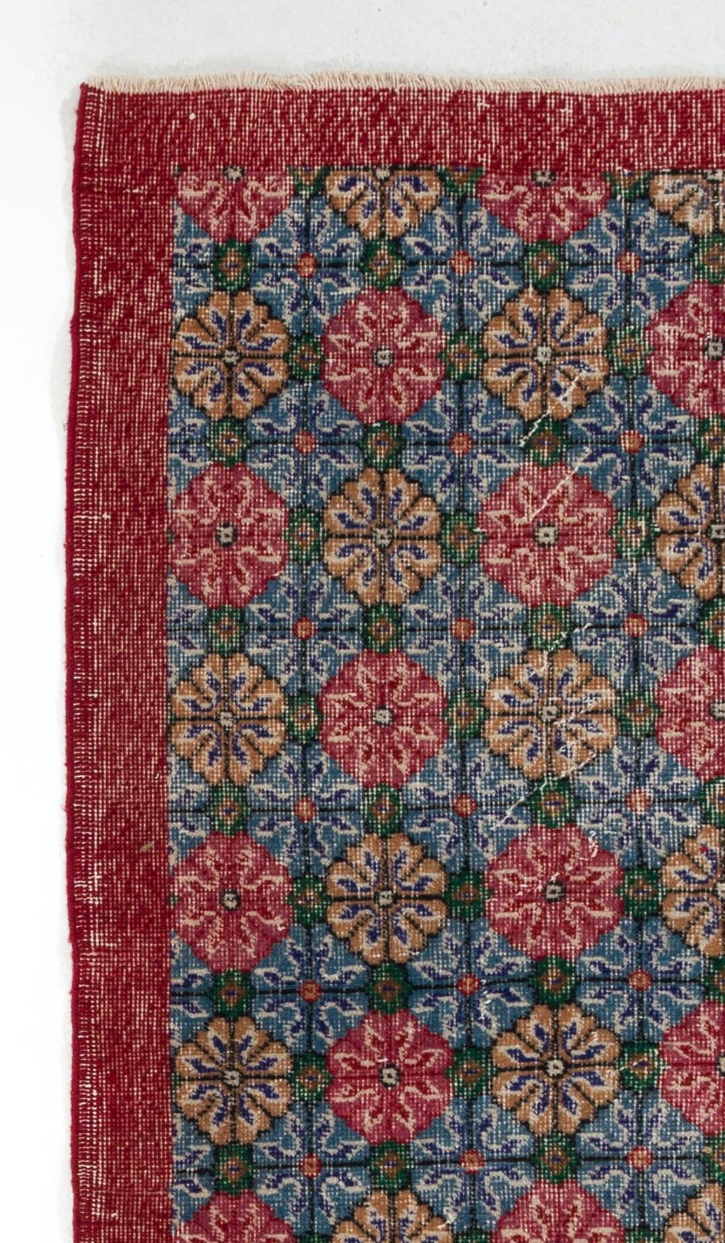 This vintage hand knotted Turkish rug features an all-over design of kaleidoscopic floral heads in red, gold, blue and green in its field and a plain main border in red.

The rug has low wool pile on cotton foundation, is sturdy, in good condition