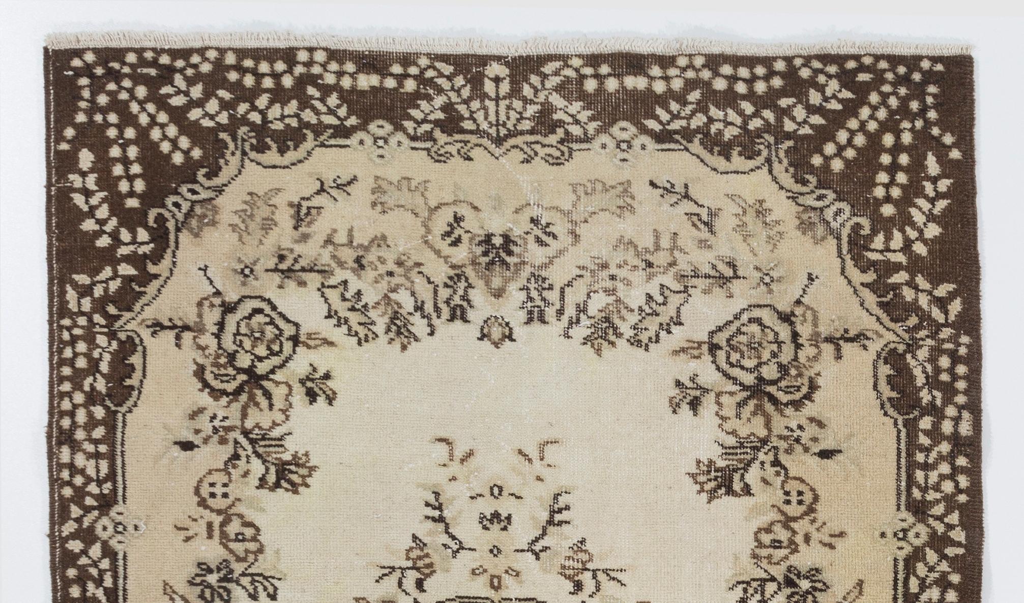 A hand-knotted vintage Turkish rug in soft colors. The rug features a floral medallion design in a field decorated with floral motifs. It has low distressed wool pile on cotton foundation, is in very good condition, sturdy and clean as a brand new