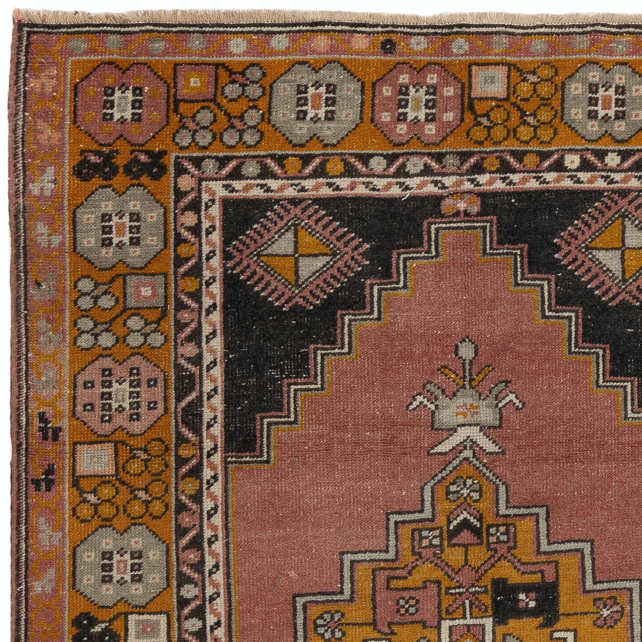 A vintage village rug from Turkey. It is made of medium wool pile on wool foundation and features two linked medallions and geometric corner pieces and a large main border in pale red/faded coral, gold and dark navy colors. Measures: 4 x 7 ft
It has