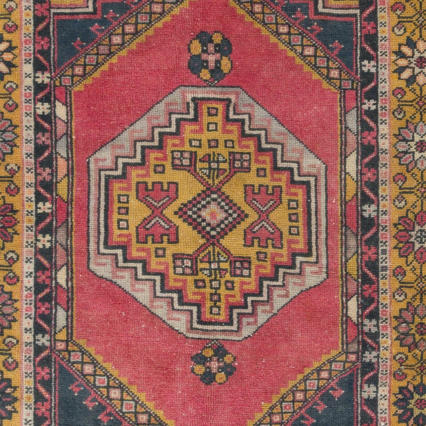 Ce tapis vintage d'Anatolie centrale présente deux médaillons reliés en or saturé avec des motifs en forme de croix à l'intérieur sur un champ uni d'un rouge doux et atténué. Les cornières en gris anthracite sont décorées de grandes palmettes