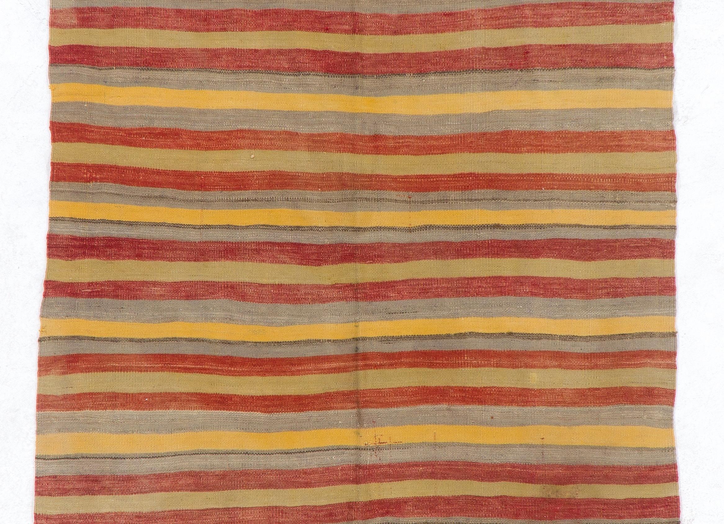 Un tappeto runner vintage a tessitura piatta, realizzato a mano in lana naturale nei toni tenui del rosso, del giallo, dell'azzurro e del verde chiaro con un design a righe. 

Il tappeto è reversibile: si possono utilizzare entrambi i lati. È lavato