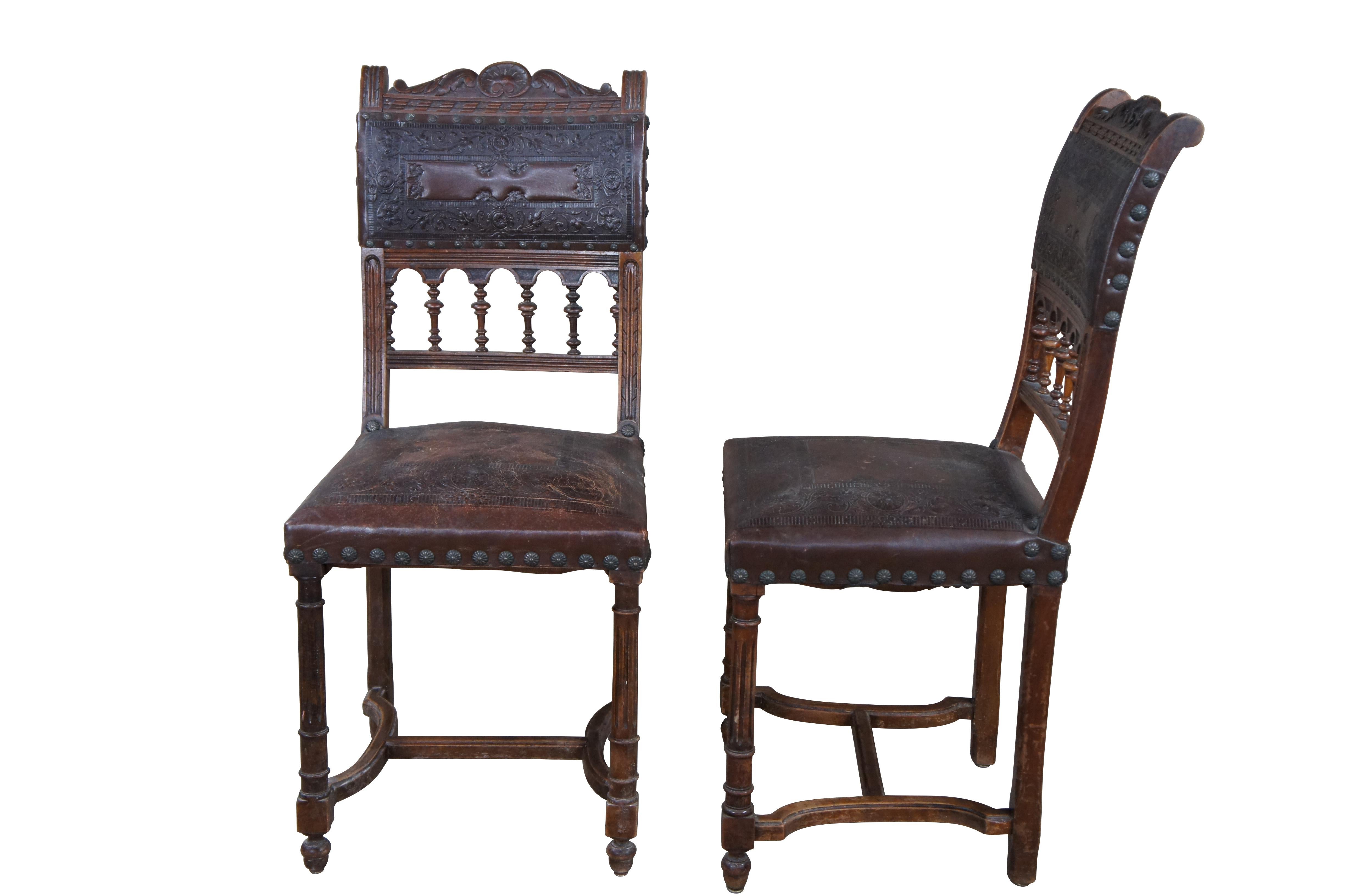 An antique set of 5 French Henry II style dining side chairs, circa 1880s.  Features an oak frame with embossed leather seat and back with pierced lower arcade accented by ornate spindles.  Each chair had nailhead trim and fluted legs leading to an
