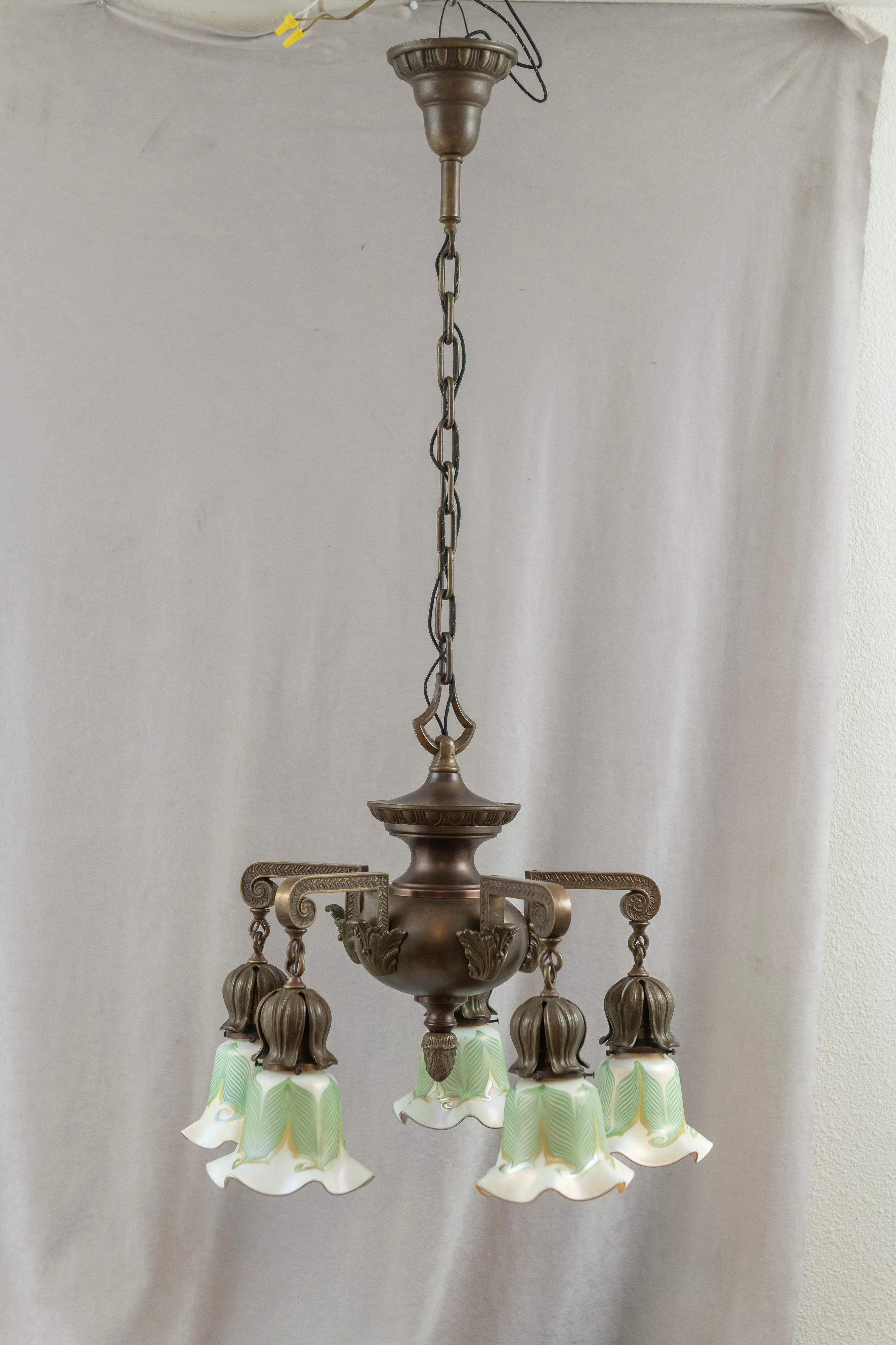 This very handsome quality bronze chandelier is complimented by 5 signed Quezal hand blown art glass shades. The chandelier is surprisingly heavy, mainly because most of the parts are cast bronze. The husks which cover the sockets are thick cast