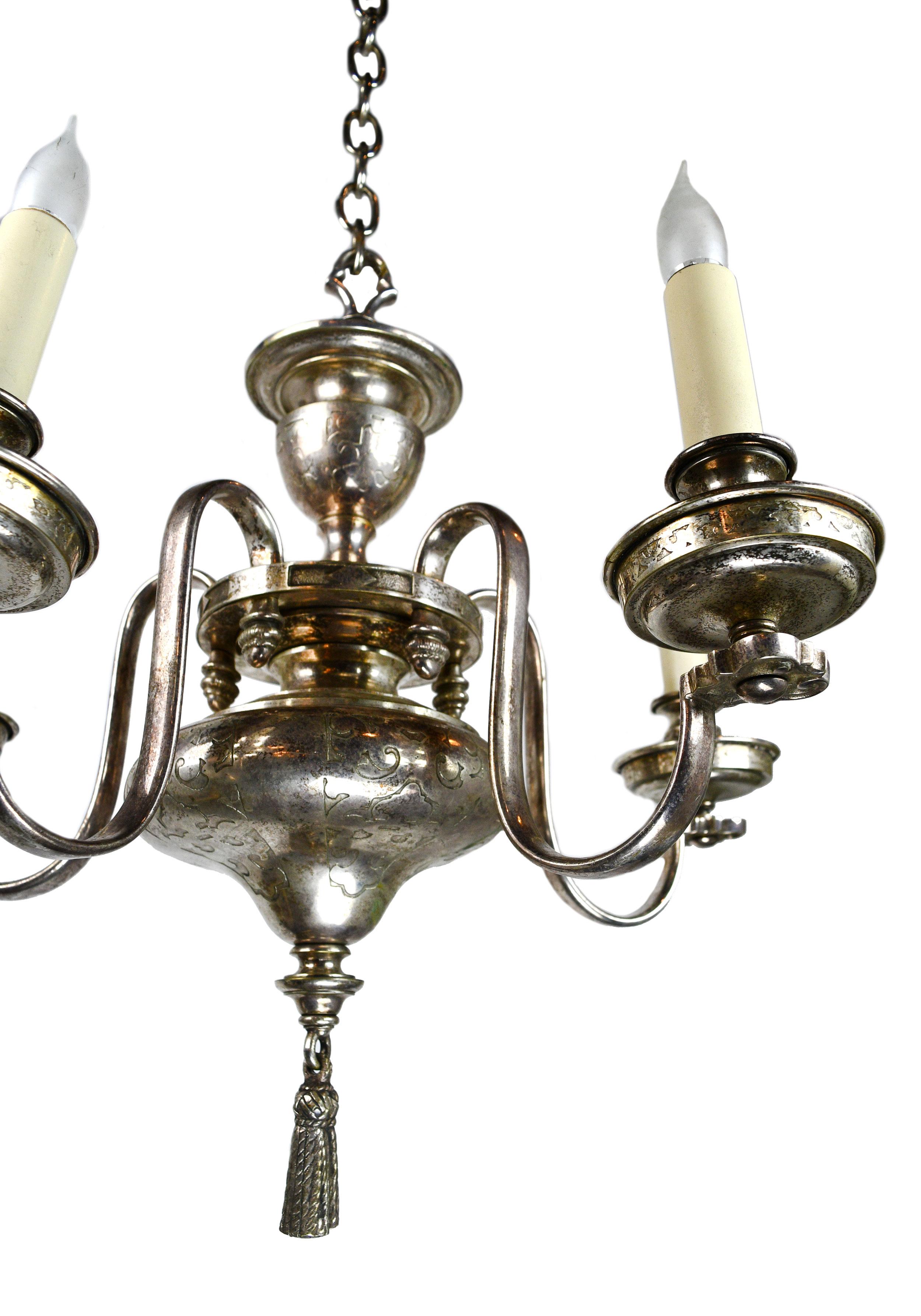 This stunning chandelier has etchings within the silver plating of the body and a lovely finial hanging below. The fine craftsmanship found through within the silver plating of this chandelier is truly eye-catching!