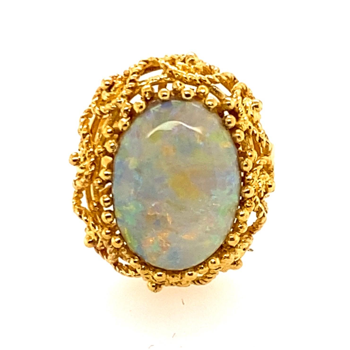 18 Karat Yellow Gold 5 Carat Australian Opal Cocktail Ring

An 18kt yellow gold cocktail ring. An intricate scroll twisted wire collet design holding a solid oval cabochon Australian opal set in a claw setting. Opal sits 10mm in height above the