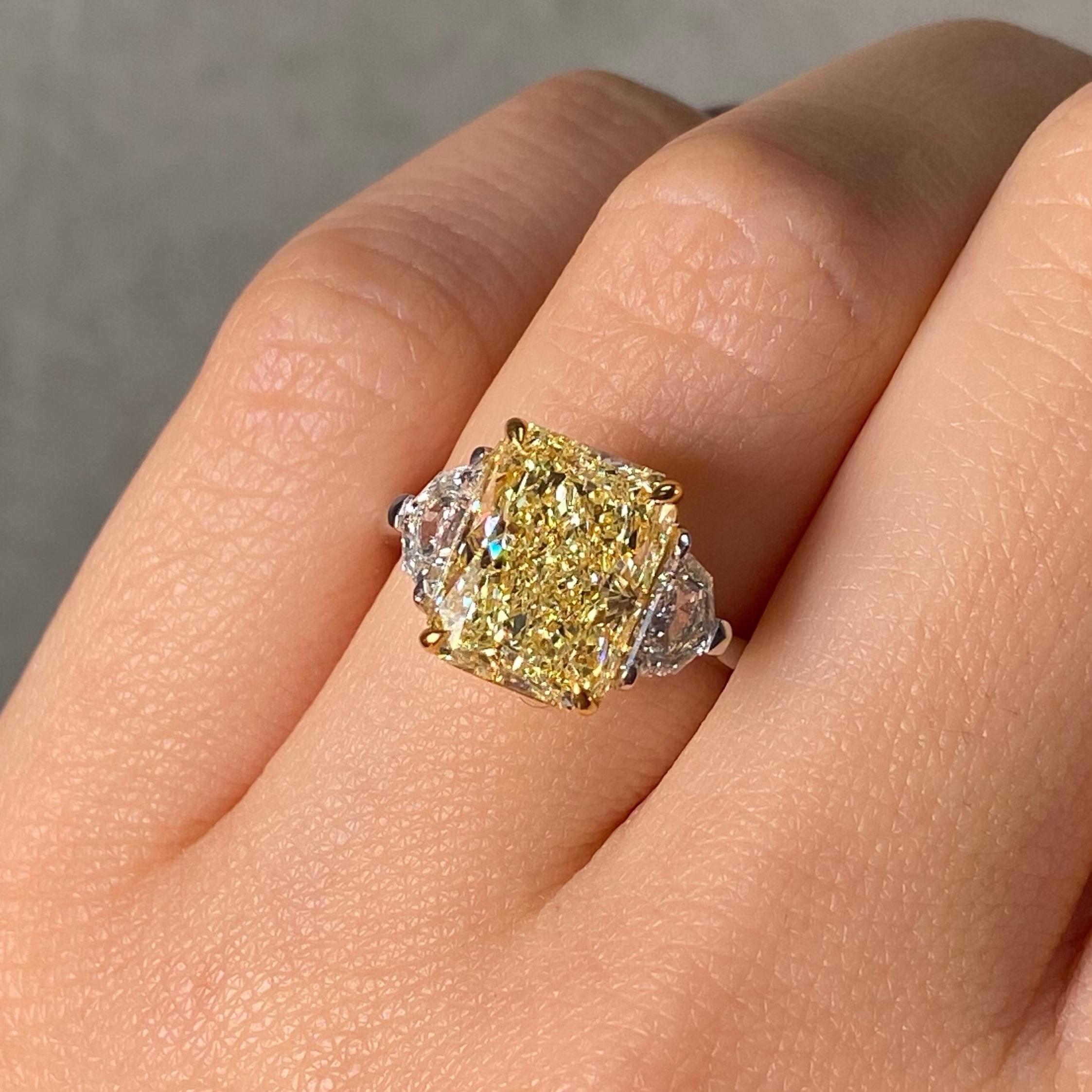 Une étude de l'équilibre et de la brillance, cette bague de fiançailles à trois pierres est centrée sur un diamant Fancy Light Yellow de 5,01 carats d'une clarté exceptionnelle VVS2. Sa teinte douce et ensoleillée est discrètement mise en valeur par
