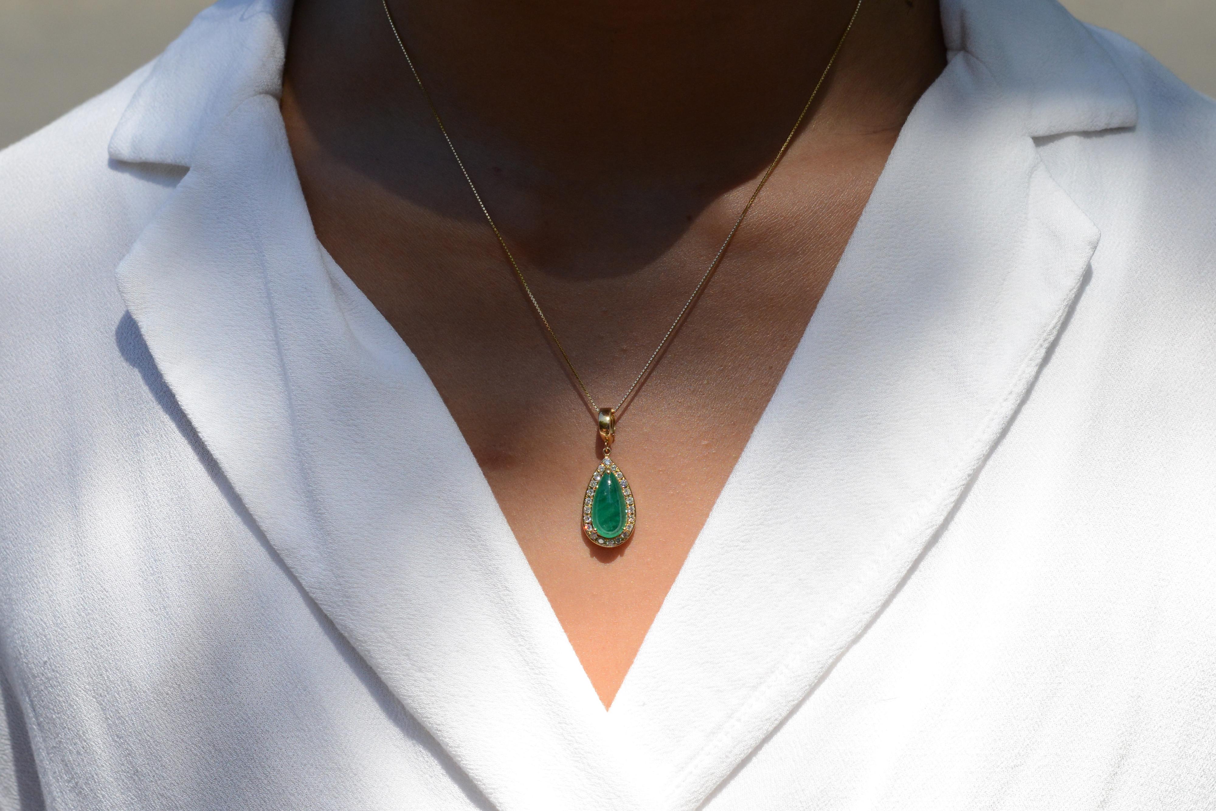This ravishing necklace features a vibrant green pear shape cabochon emerald in elegant 18k yellow gold. The setting is illuminated with 22 colorless diamonds that beam off your neck. This pendant is a versatile piece with a hinged enhancer bail