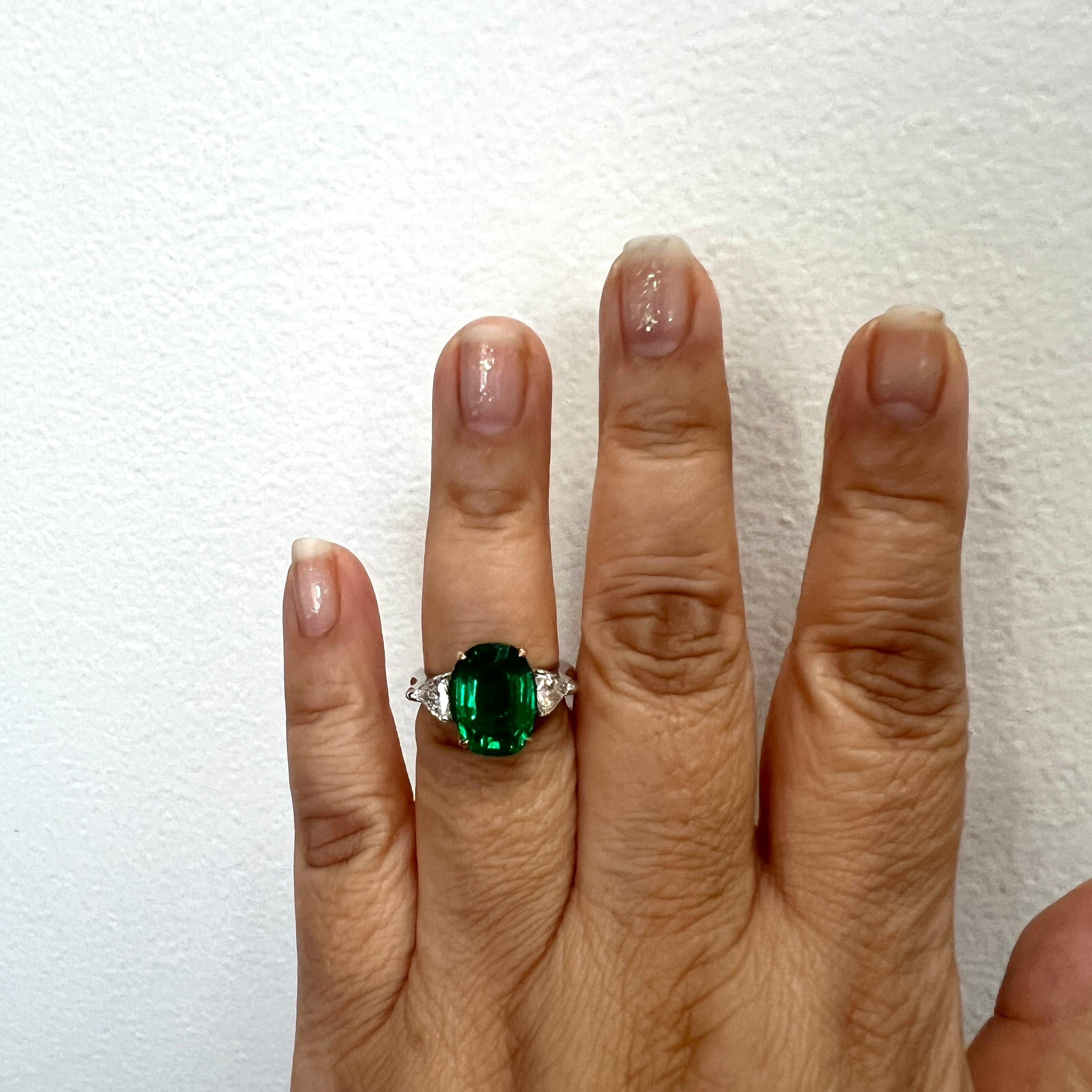 Gorgeous 5.61 ct. emerald oval with two white diamond trillions.  Handmade in 18k yellow and white gold.  Ring size 6.5.
