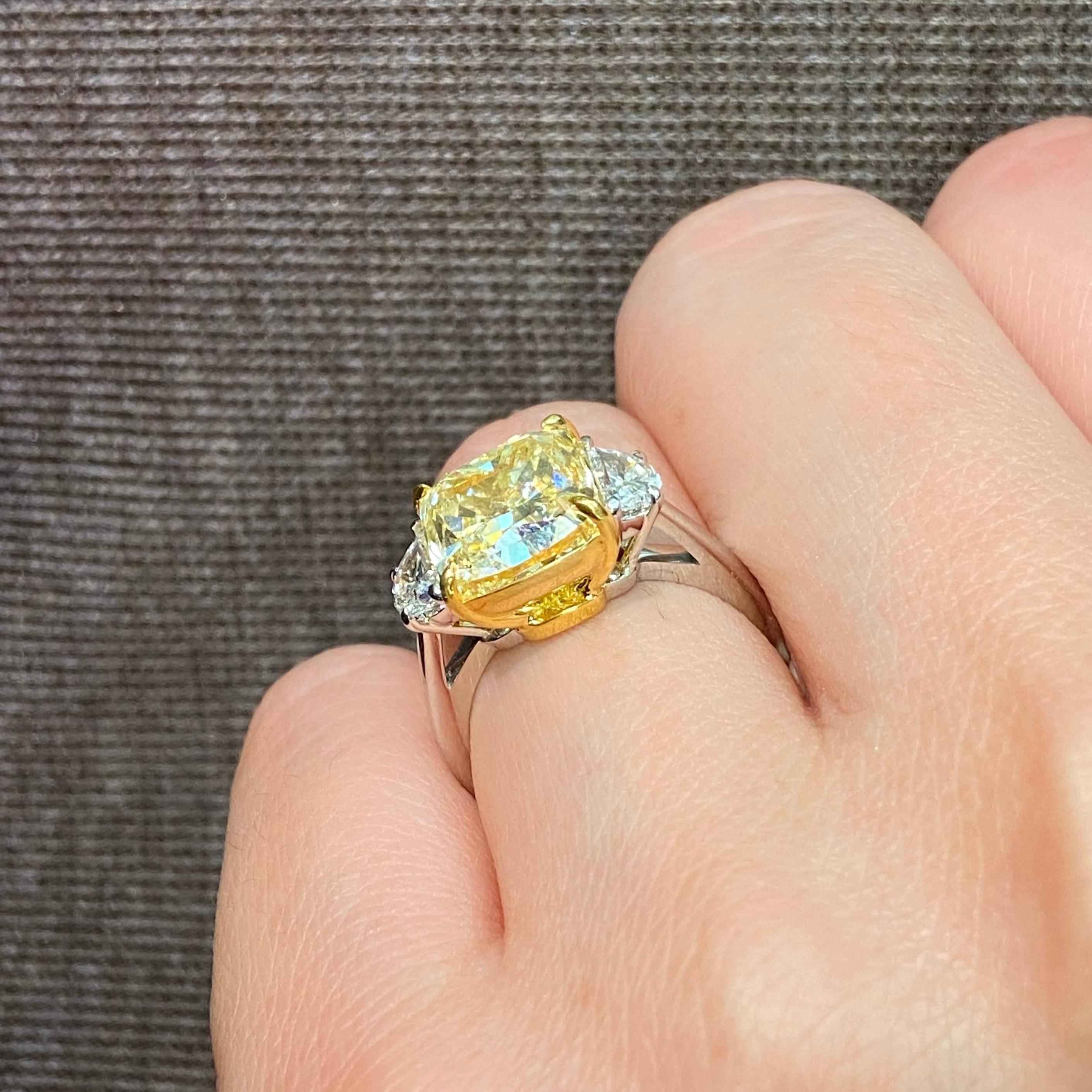 Introducing a breathtaking 5.03 Carat Fancy Yellow Elongated Cushion Cut Diamond, elegantly set in this exquisite three-stone ring. This GIA Certified masterpiece features VVS1 clarity, ensuring a radiant brilliance that catches the eye and captures