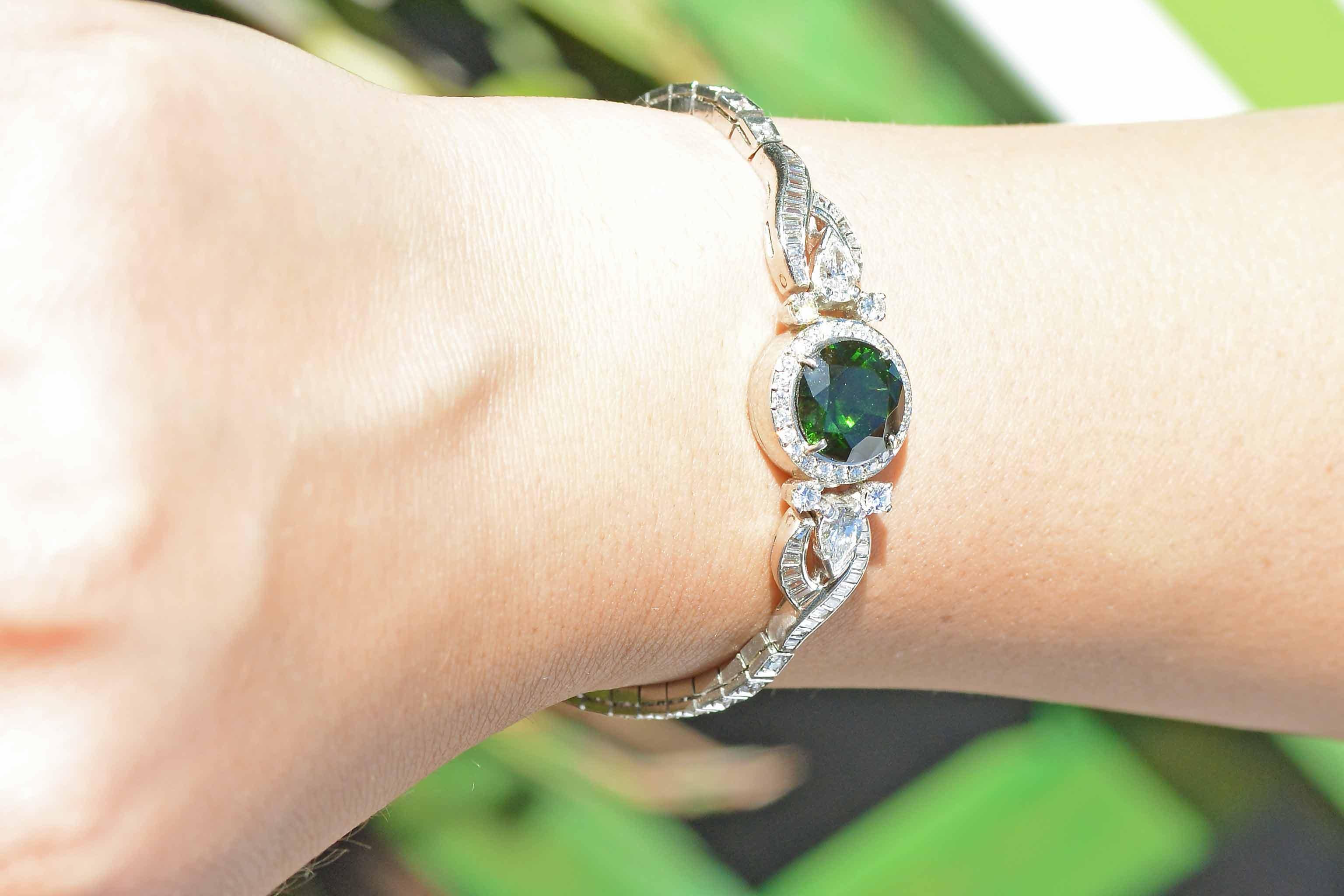An eye catching and truly one of a kind Art Deco tourmaline bracelet. This exquisite 1920s cocktail jewel centered by a verdant, pine forest green 5.10 carat natural gemstone and is set in a complementary halo of round brilliant and pear cut