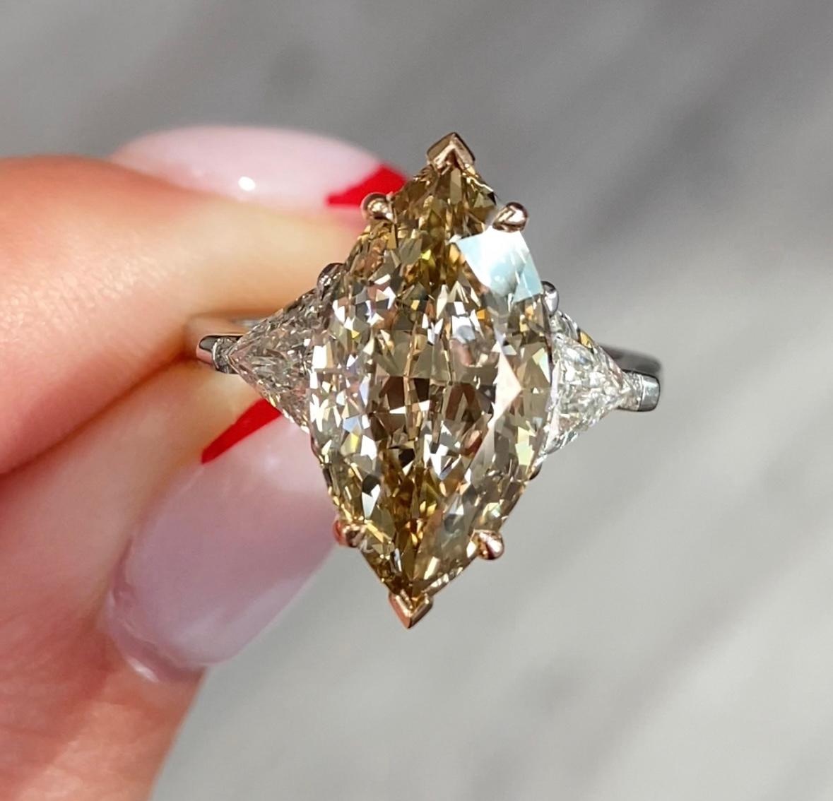 One of a kind marquise cut champagne diamond certified as Fancy Yellow Brown, with a pleasant color. 
VS2 quality,  Excellent + Excellent cutting and no fluorescence. 
Set in a platinum shank topped with a rose gold gallery
Side stones are 1ct total