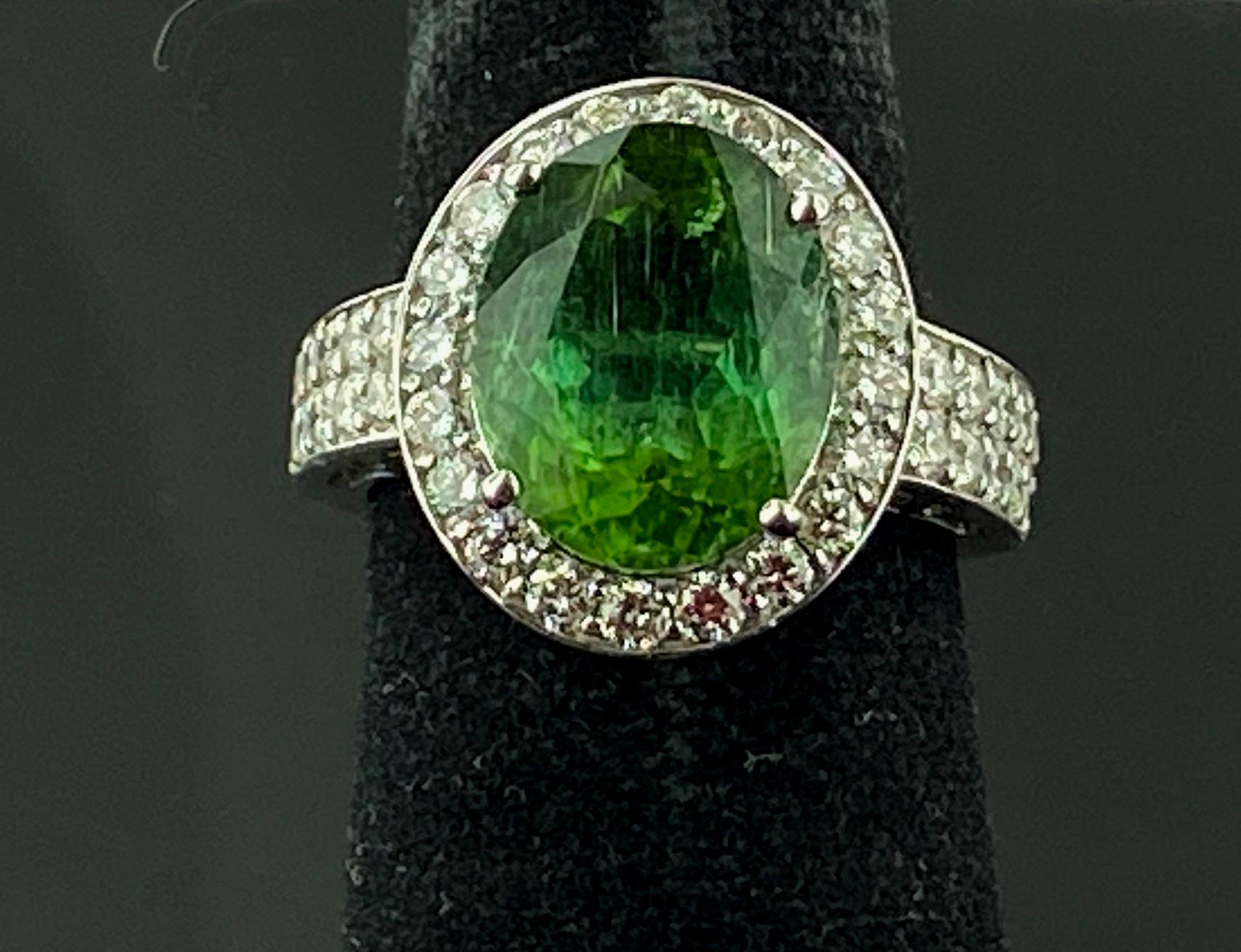 Set in 14 karat white gold, weighing 7.18 grams, is one 5 carat Oval Cut Green Tourmaline with 44 Round Brilliant cut diamonds weighing approximately 1.33 carats, Color: G-H, Clarity: SI-1.  Ring size is 6.5.