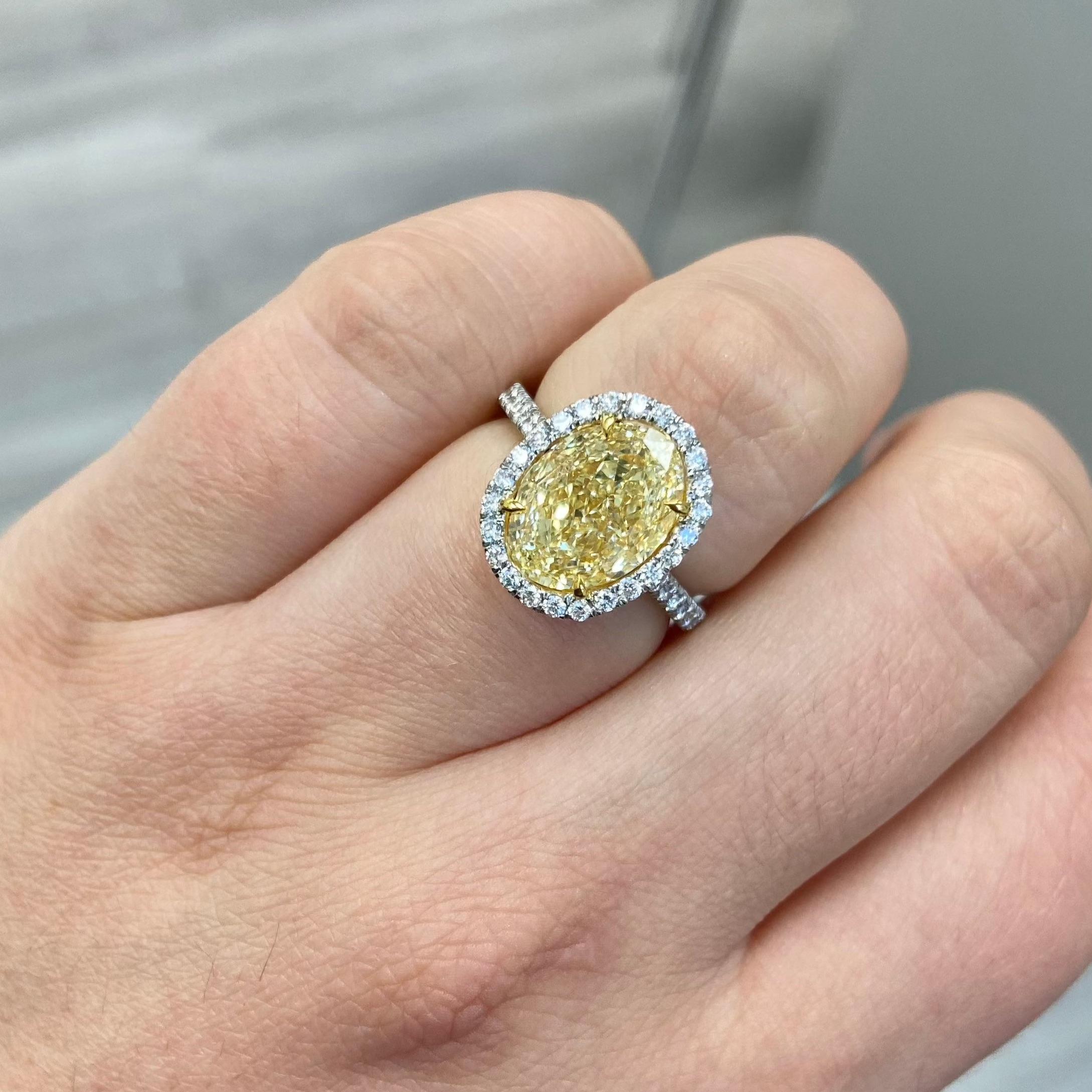 Exceptionally well cut oval with no bow tie and full of fire. Set in a Platinum ring with a Yellow Gold basket making it face up as a Fancy Yellow!

5.03 Carat Light Yellow (WX) Oval 
VS1 Clarity 
0.68 Carats of Surrounding Diamonds
Set in Platinum