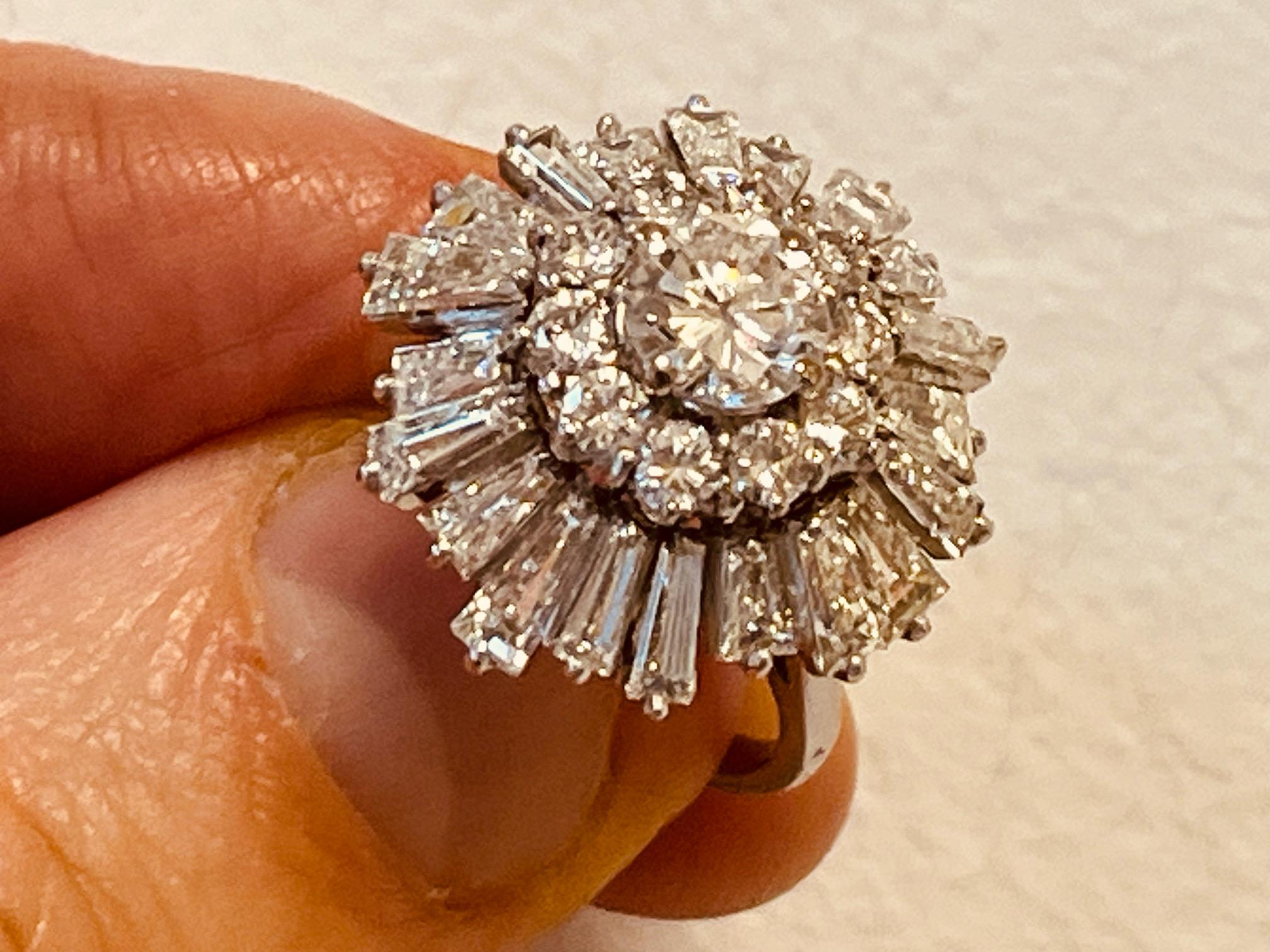 A diamond ballerina cluster ring, mounted in platinum. The undulating tapered baguette border to a brilliant cut diamond centre with brilliant cut surround. Smaller diamonds aprox 4 cts. The centre round diamond with GIA certificate stating it is