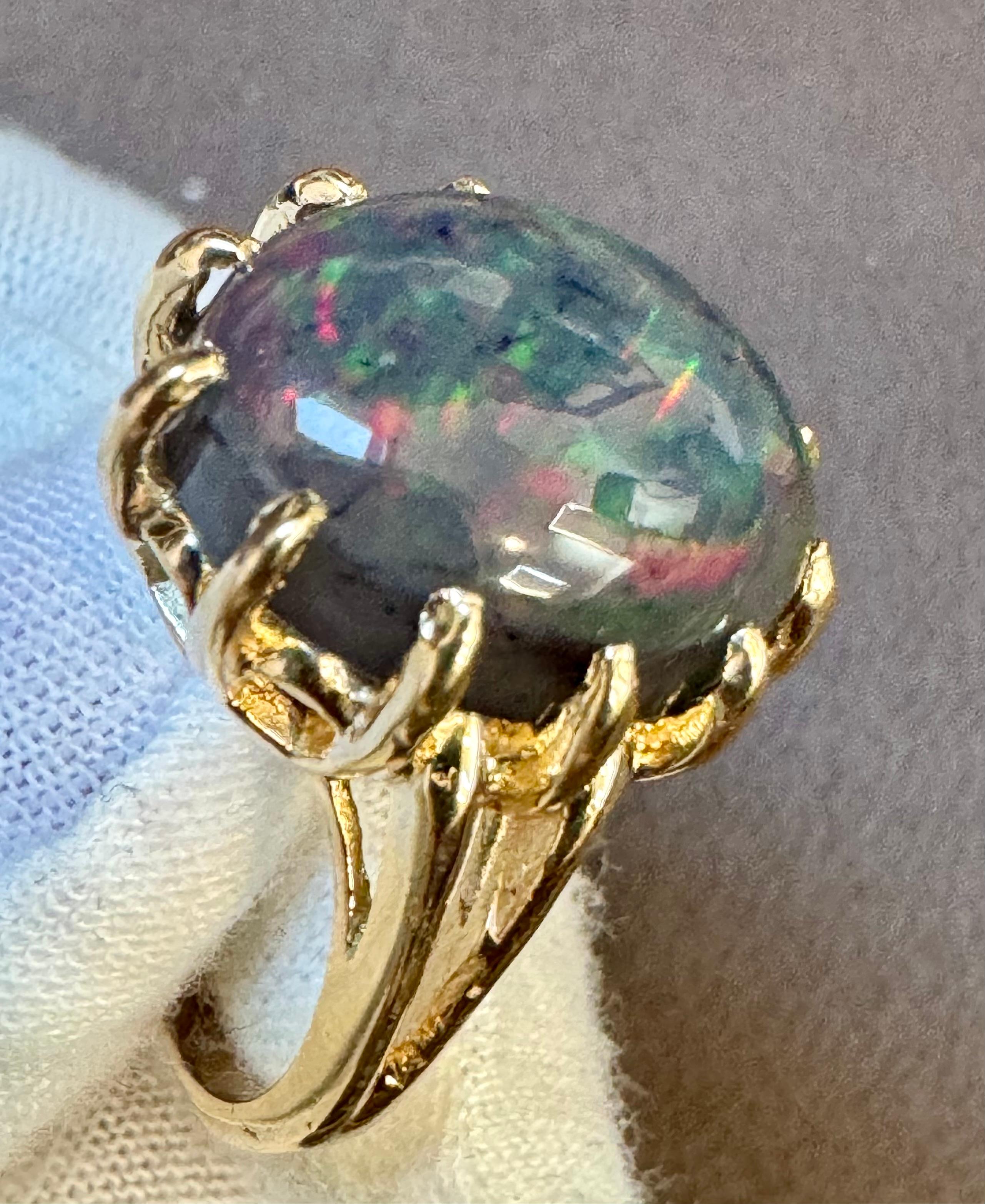 Introducing our captivating 14 Karat Yellow Gold Cocktail Ring featuring a breathtaking 5 carat oval-shaped Black Australian Opal Cabochon . This remarkable piece showcases the opal's mesmerizing shades of green and blue, radiating with a brilliant