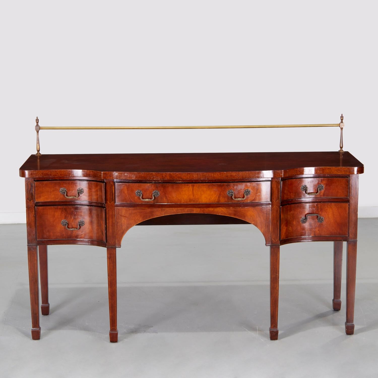 20th c., Federal style mahogany sideboard, possibly Baker, with original brass rail gallery, shaped front, inlaid stringing, and original brass drawer pulls, unmarked. While this may be considered a somewhat subdued version of a sideboard of this