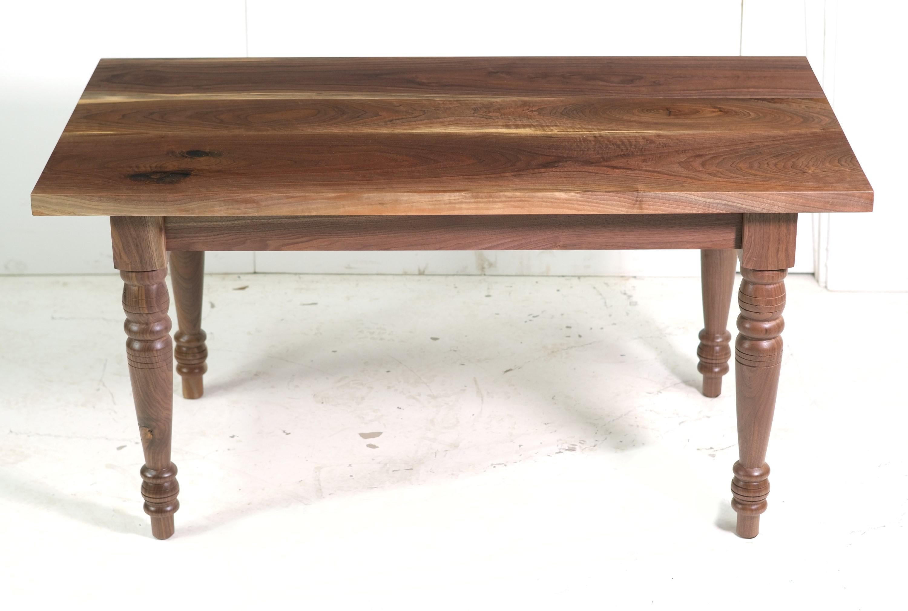 Solid walnut table features a three piece walnut top complete with turned legs. Satin finish. Please note, this item is located in our Scranton, PA location.