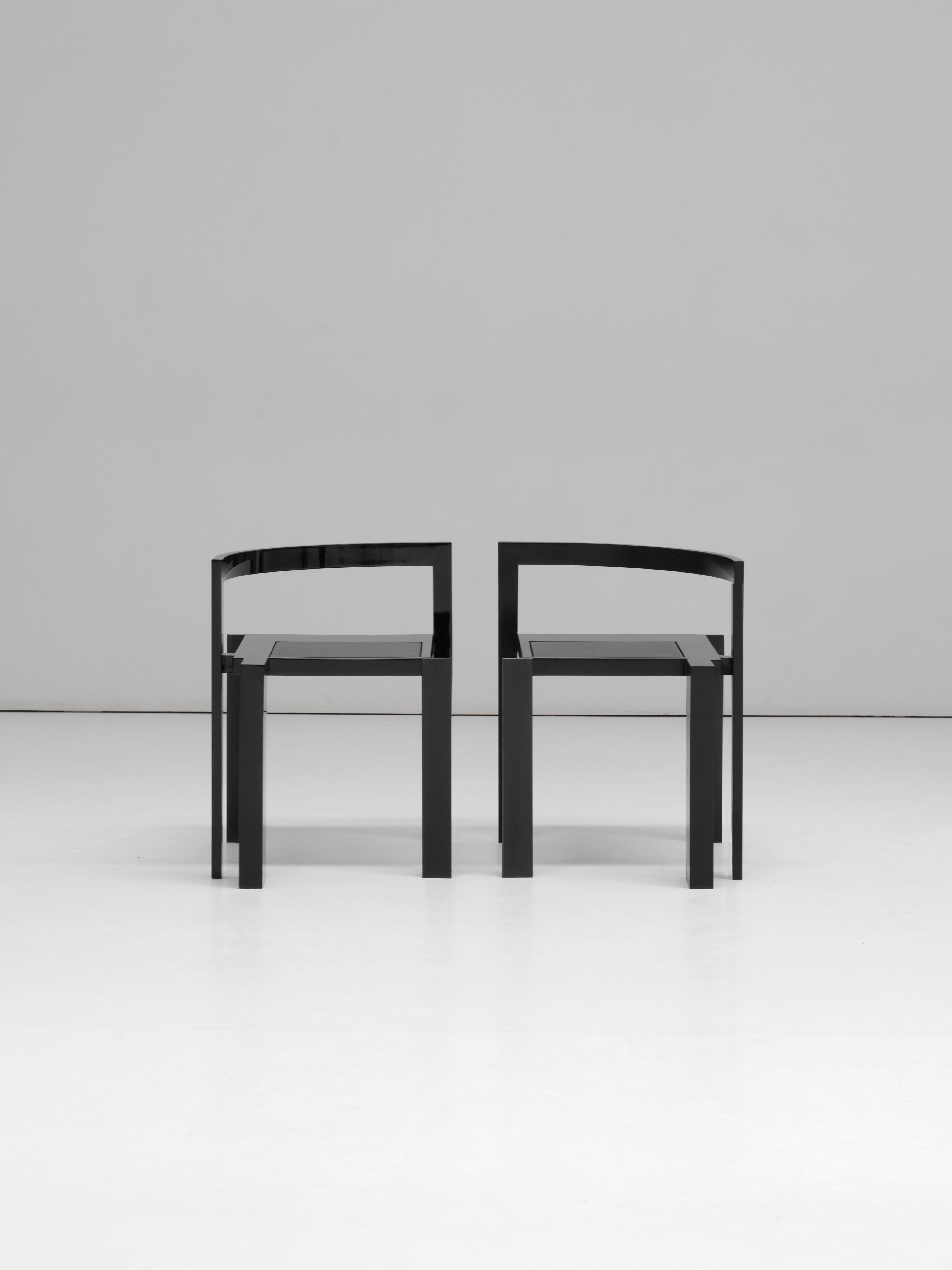 The chair is accommodated by the column. Its form is made up of a composition of intersecting geometries, an incomplete circle curves up from its rectilinear seat and extends outwards to hug the column. The five legs are of changing thickness, three