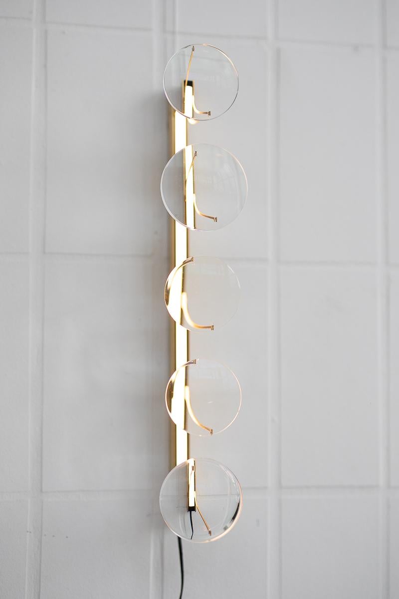 5-lens wall lamp by Object Density
Handmade
Dimensions: 7.5 x 14.5 x 43 cm
Material: brass (messing), optical lenses, dimmable 12V LED

Through a close inquiry into an optician’s process and production, Object Density have realised the