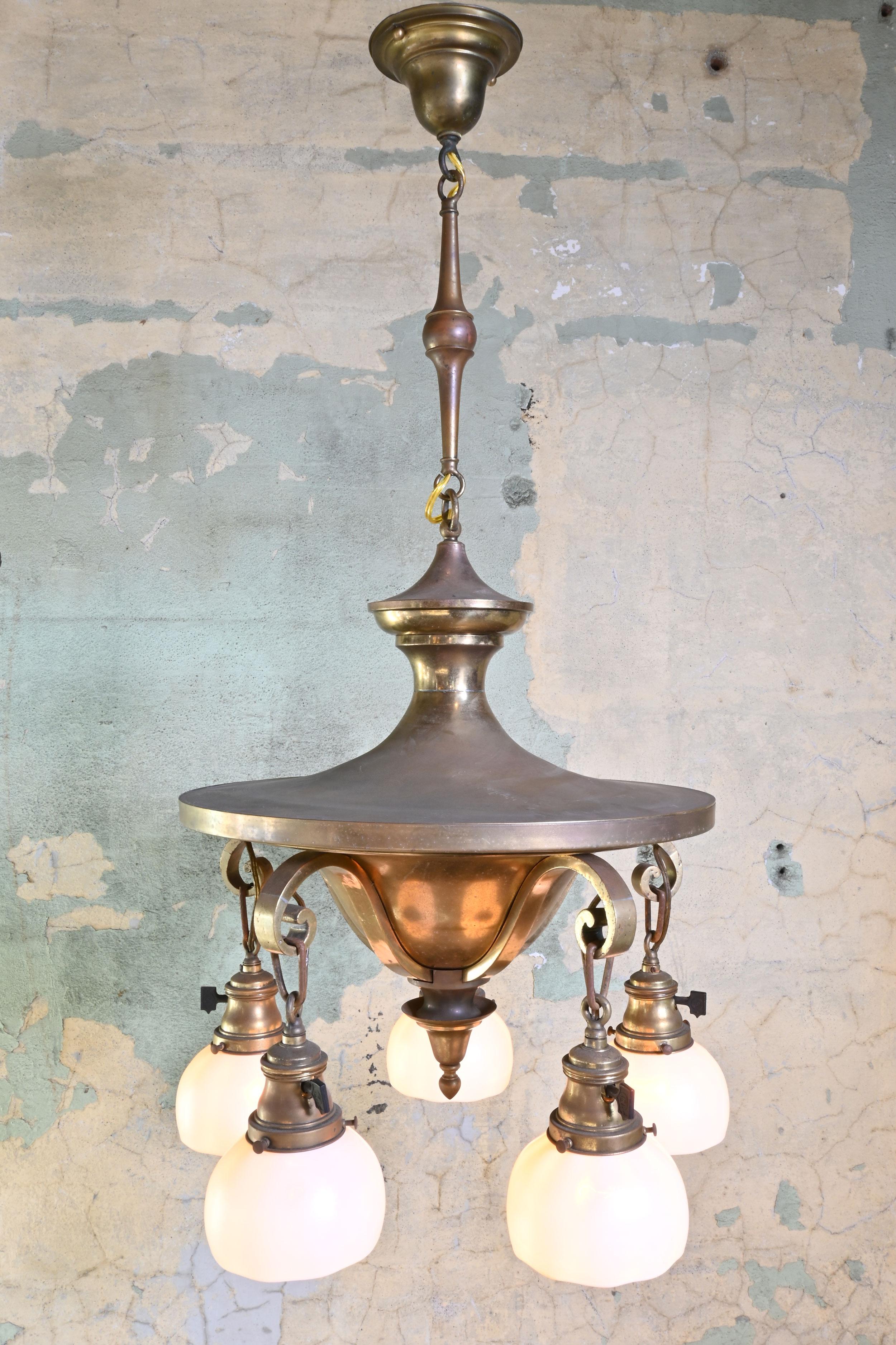 This Arts & Crafts fixture is of a circular design, lending it to be of a more classical design inline with other pan fixtures. This 5 light features Steuben Calcite shades that look white but give off a pink glow with the yellow/orange incandescent