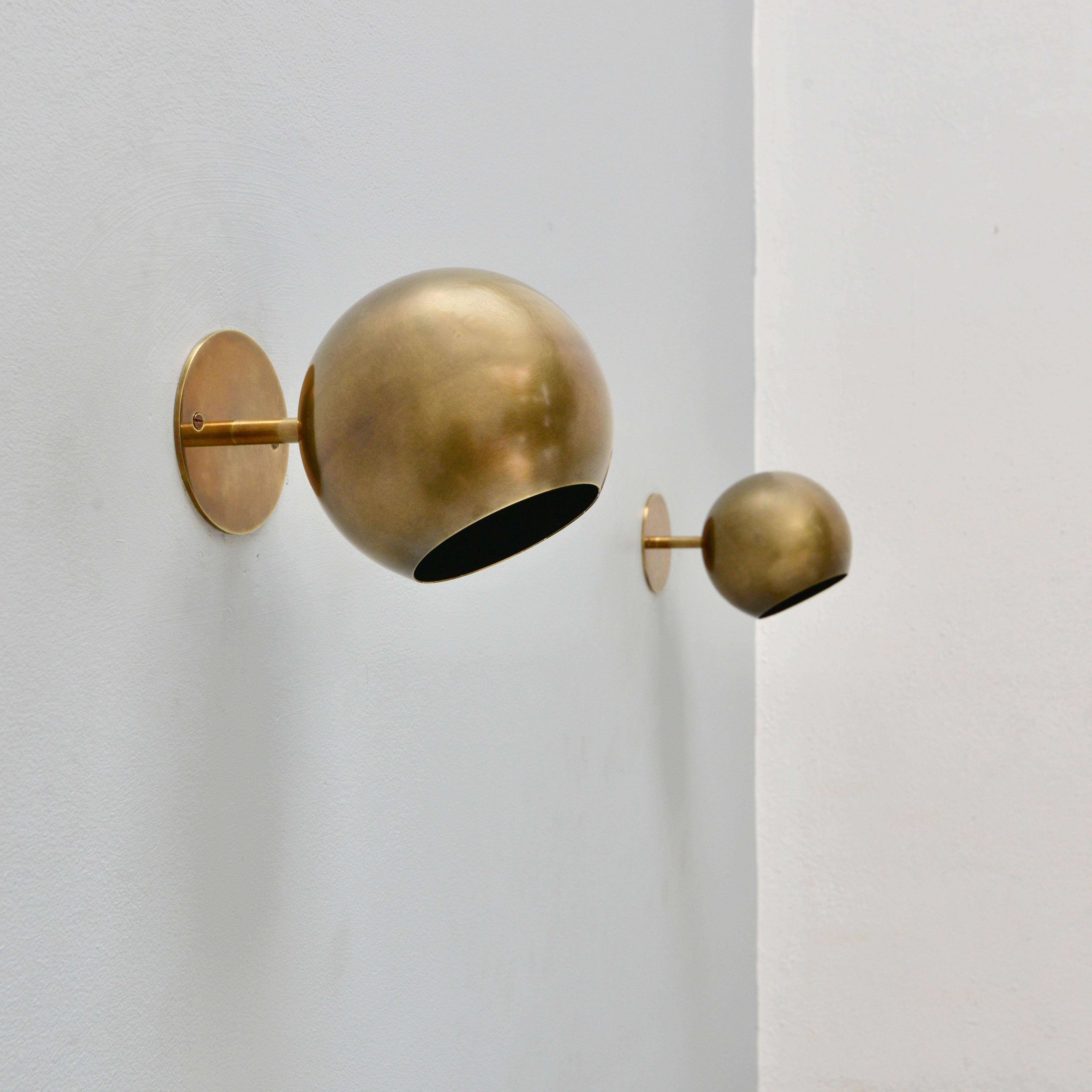 (4) Classical American small globe sconces from the 1950s by Lightolier. These sconces are in an aged solid brass finish and construction. Partially restored with 1 E26 medium based socket per sconce, for use in the USA. They can also be wired for