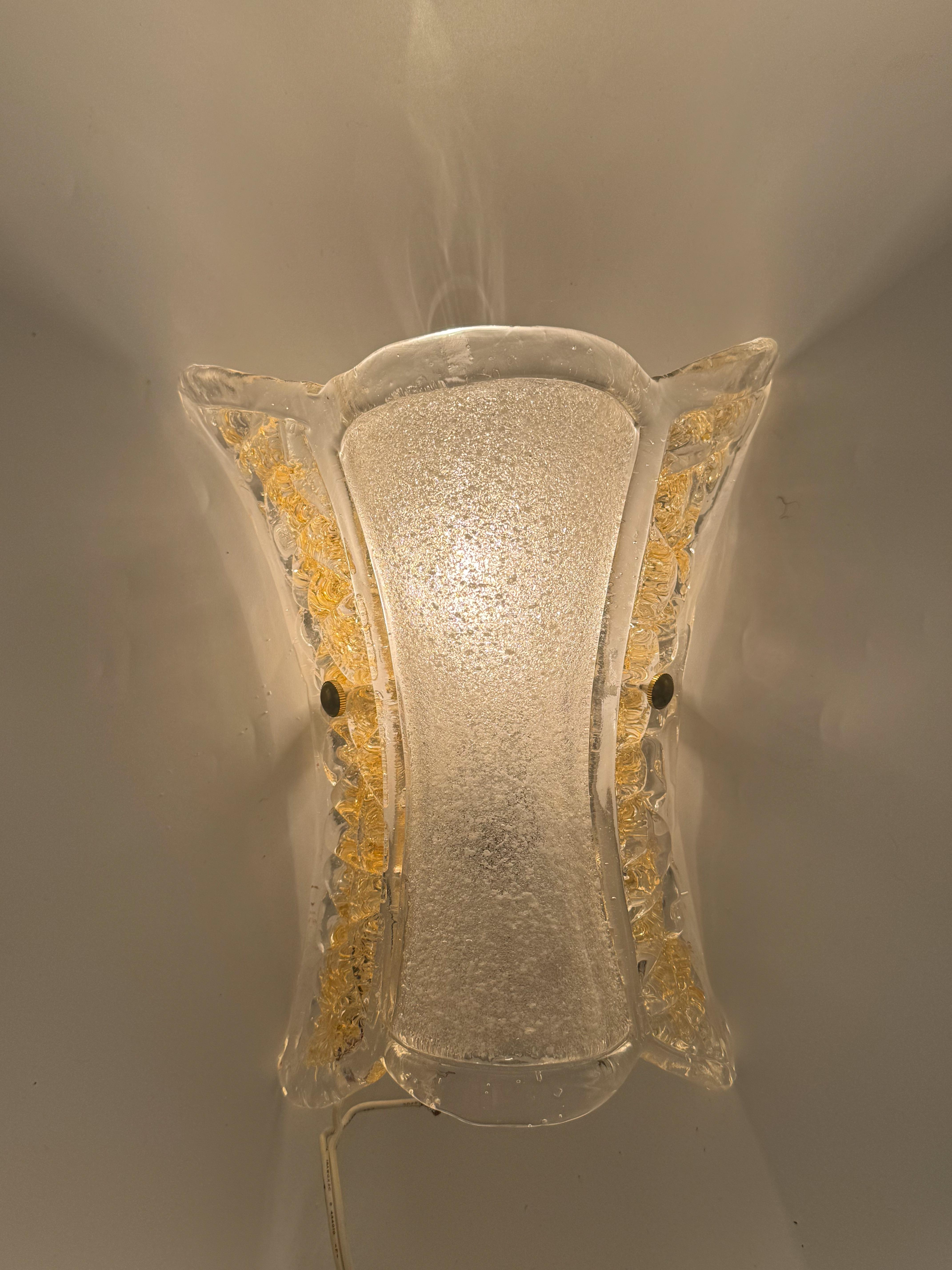 Raro y excepcional grupo de cinco apliques de cristal de Murano de Venini, fabricados en Italia en la década de 1970. Cada aplique tiene una pantalla cónica soplada a mano con una silueta acampanada, compuesta de cristal transparente labrado a mano.
