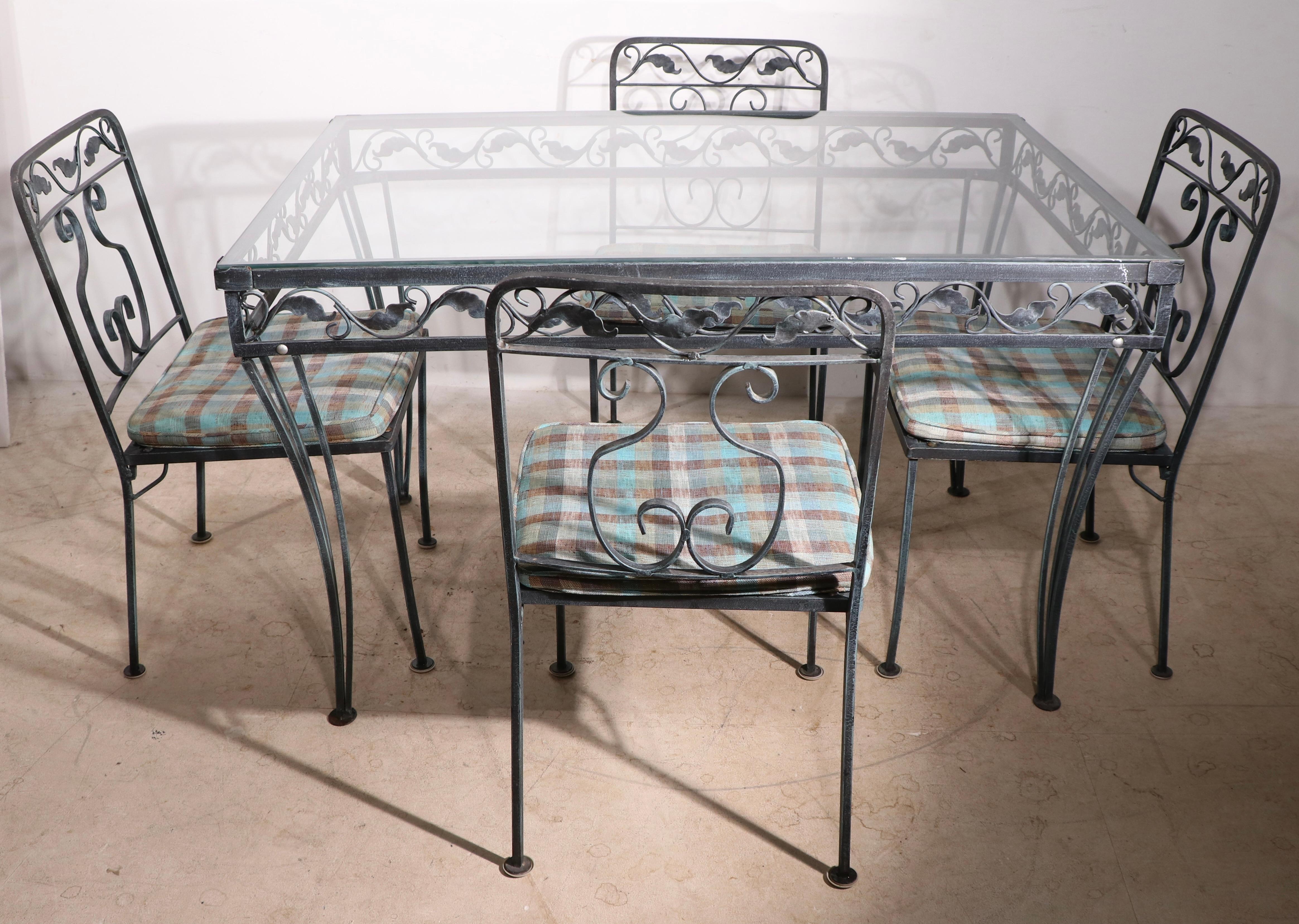 Chic garden, patio, dinette set consisting of a dining table , and four side chairs. The table has a tempered glass top, the chairs have their original upholstered pad seats, metal executed in faux Verdigris finish . Made by Medowcraft, in the style