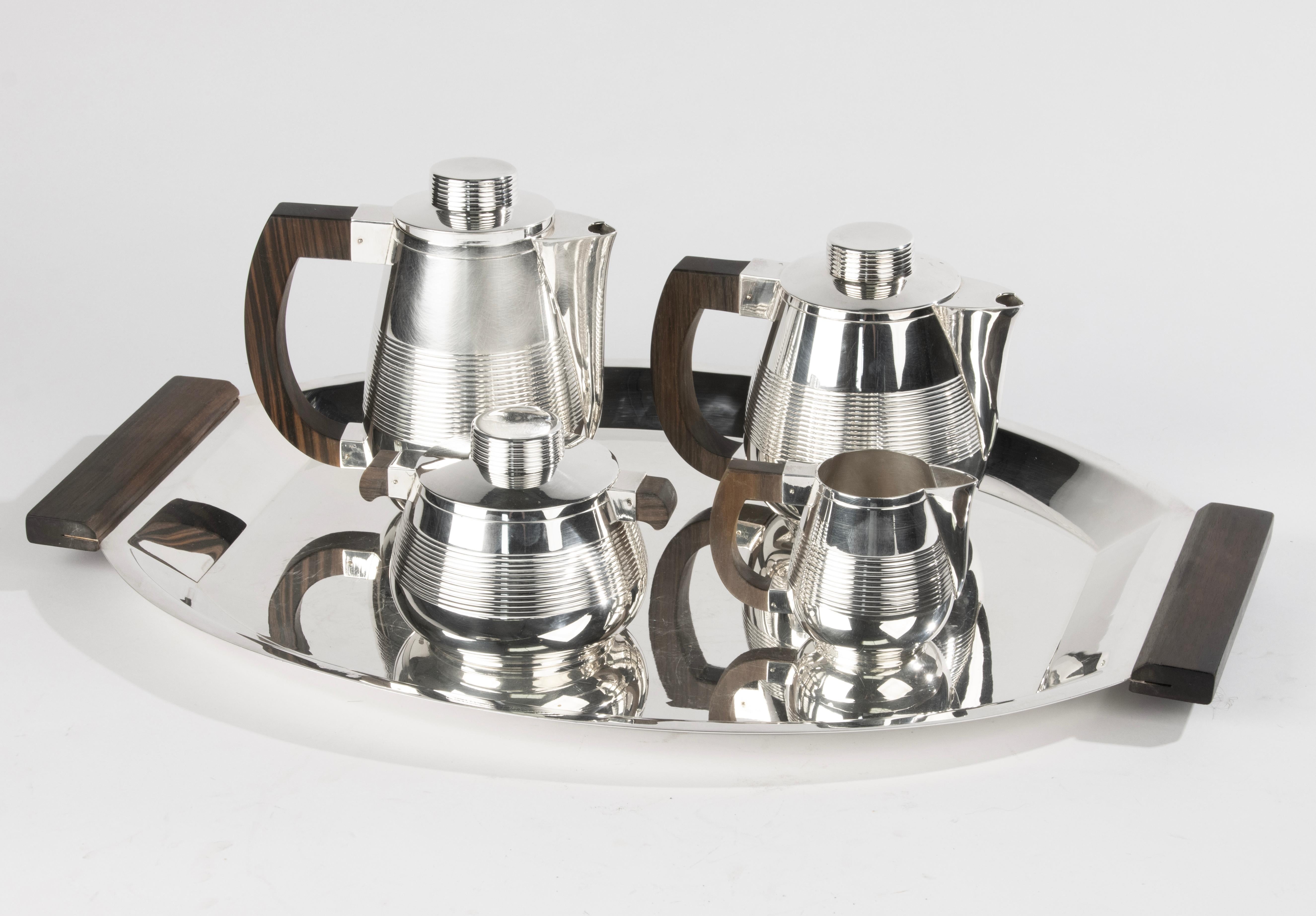 Elegant five-piece French silver-plated tea and coffee service from the Art Deco Period. The set includes a coffee pot, teapot, sugar bowl with lid, milk jug, and a large oval tray with wooden handles. Each piece features a striking contrast between