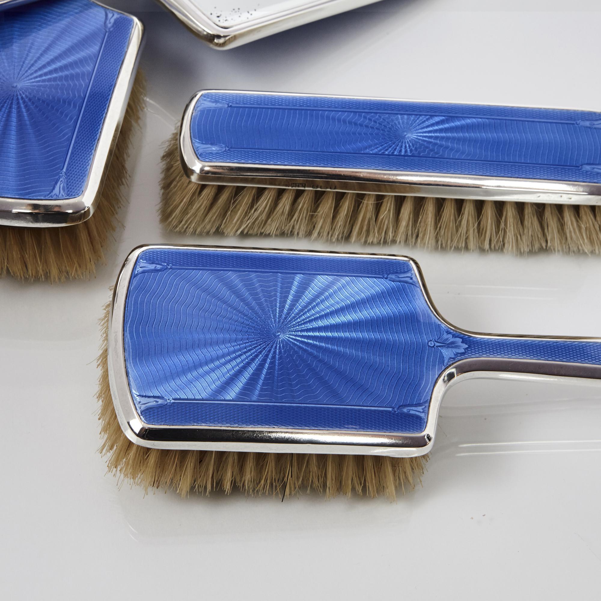 Classic, five-piece, blue enamel silver dressing table set comprising two hair brushes, two clothes brushes and a hand mirror, all in original and excellent condition. Each piece is finely engraved with engine-turned patterns and incorporates