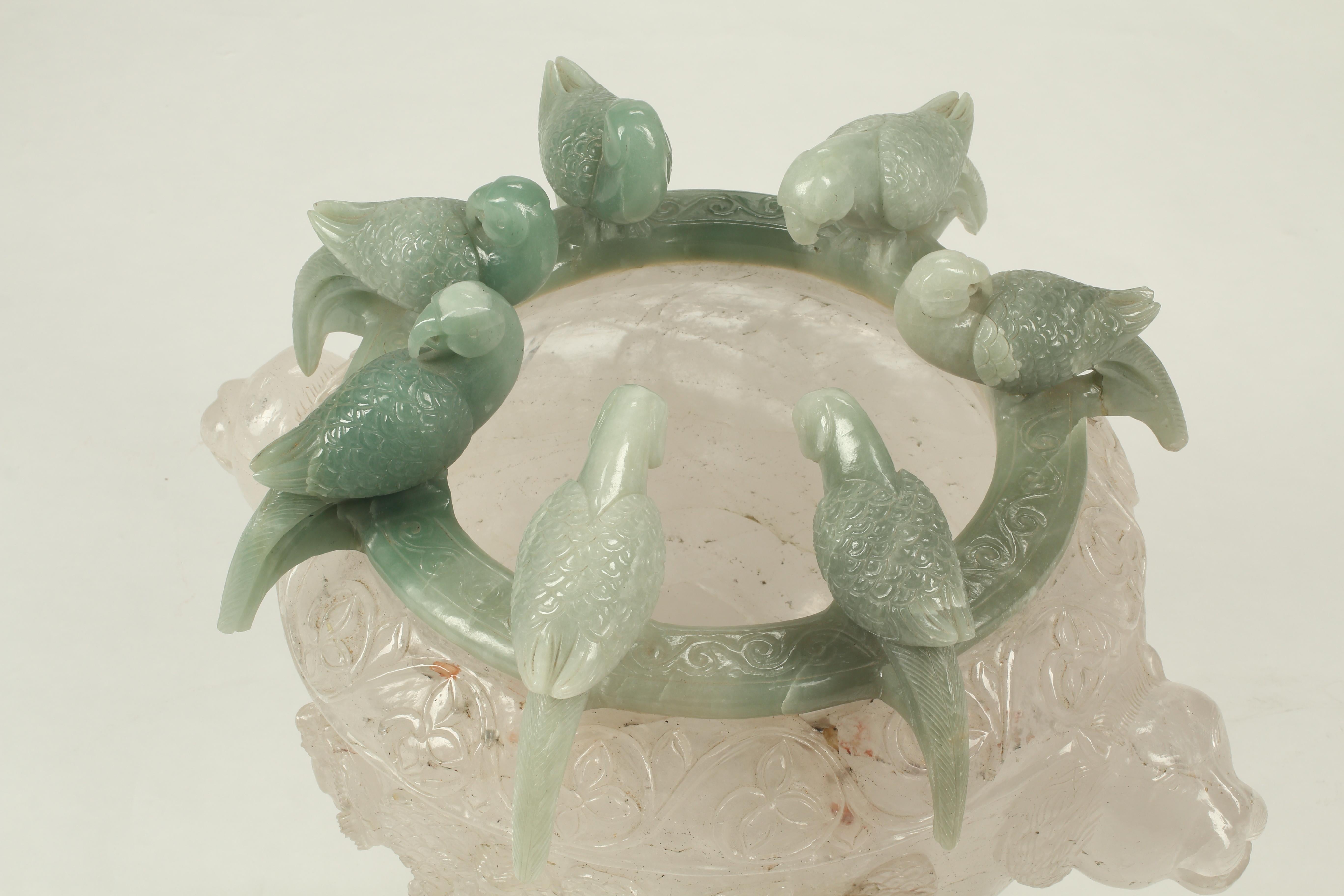 Une urne unique, sculptée à la main, en cristal de roche continental et jaspe vert. L'urne est surmontée de plusieurs sculptures d'oiseaux très détaillées, taillées à la main dans du jaspe vert. Les oiseaux sont perchés autour du bord et représentés
