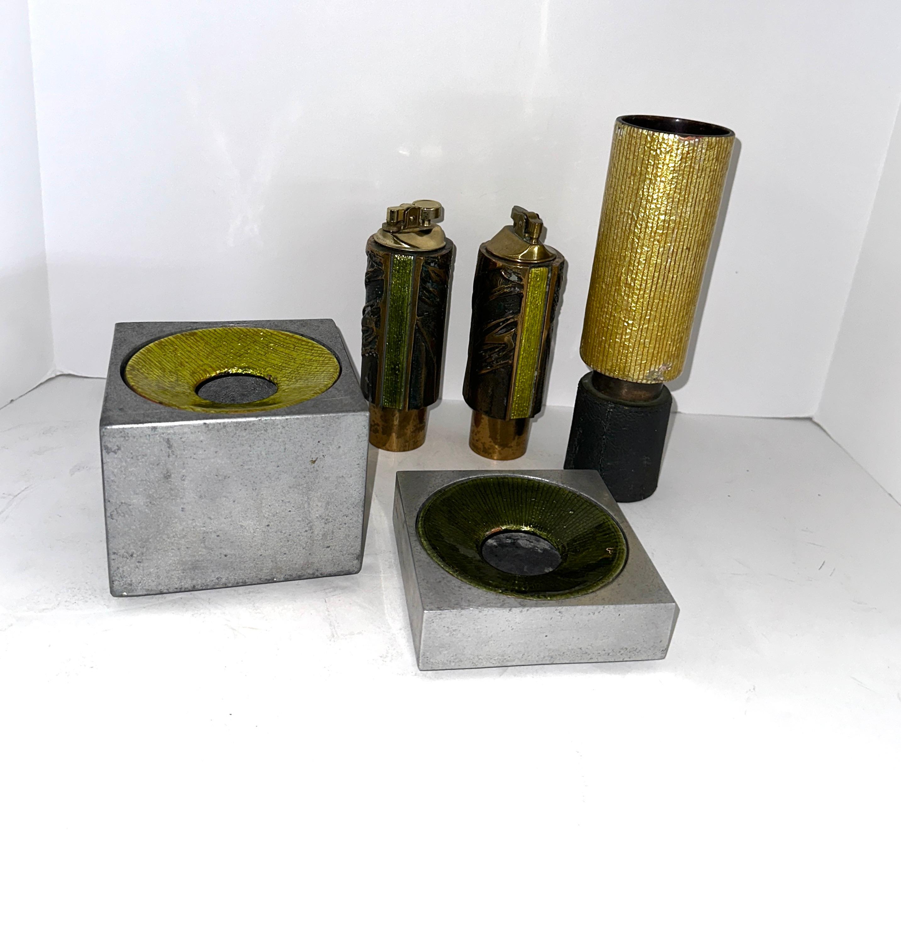 A lovely collection of 1960’s Studio Del Campo enameled pieces. There are 5 pieces, 2 lighters, 2 ashtrays and a bud vase. The vase and lighters are likely bronze or brass based, the ashtrays are some sort of white metal. 
The enamel on the two