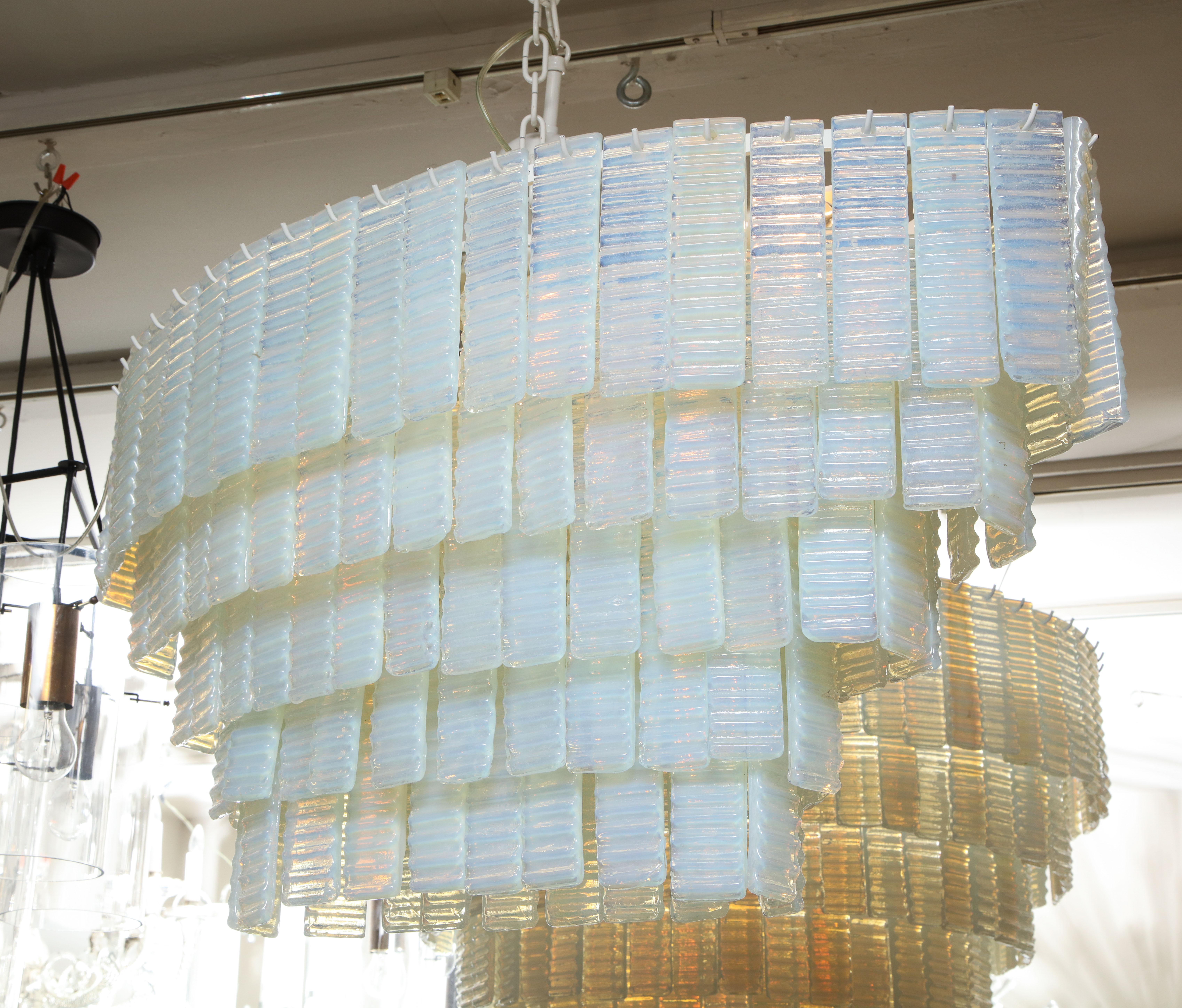 Custom 5 tiered corrugated opalescent Murano glass chandelier in an oval shape. Each opalescent glass piece is carefully handmade by the glass artisans in Murano, Italy. 8 standard socket (E12) on the frame to illuminate the chandelier for the