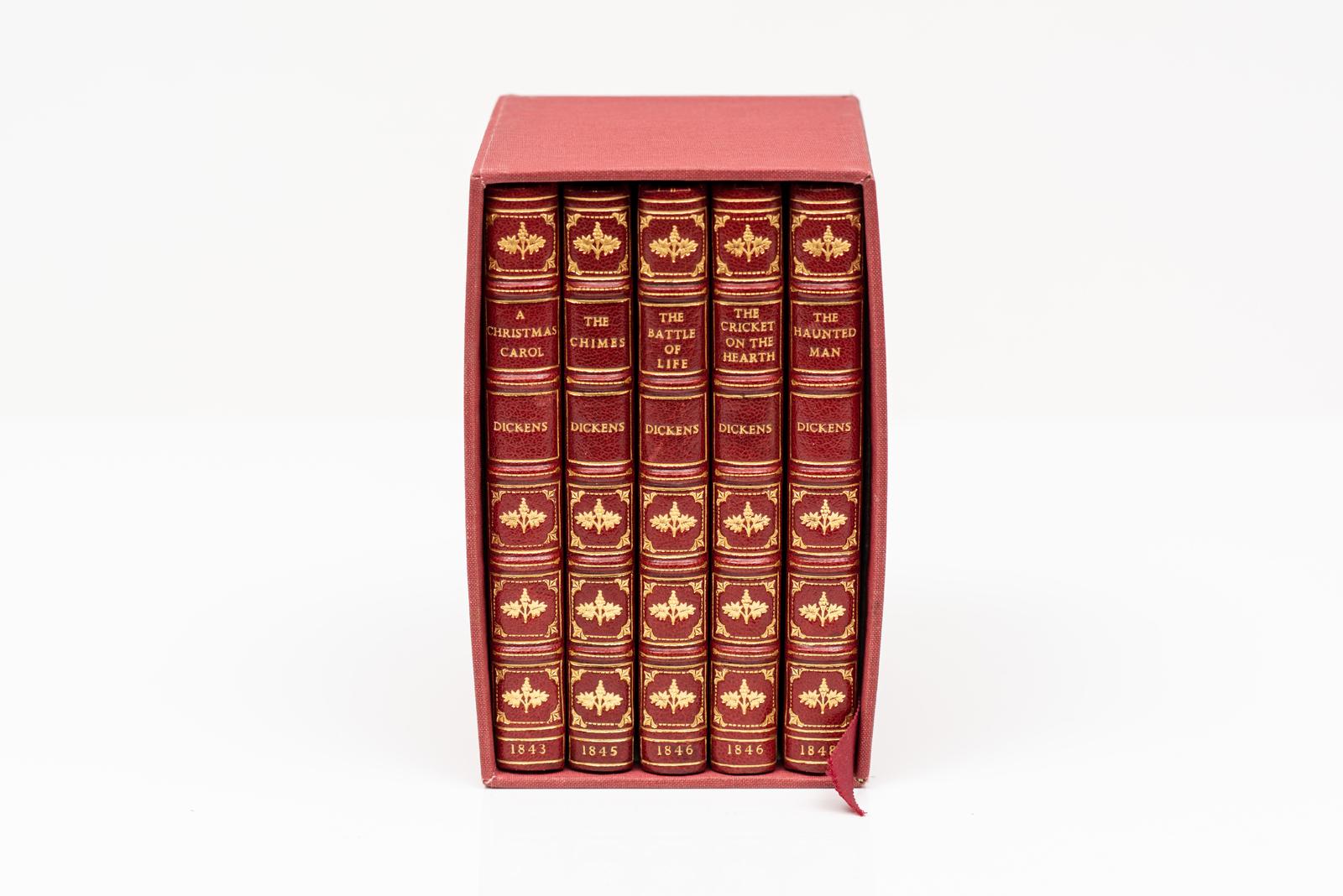 5 Volumes. Charles Dickens, The Christmas Books. Bound by Bayntun in full red morocco. Original covers bound in the rear. Ornate gilt-tooling on the covers and raised band spines. All edges gilt. Frontispiece and illustrations throughout by John