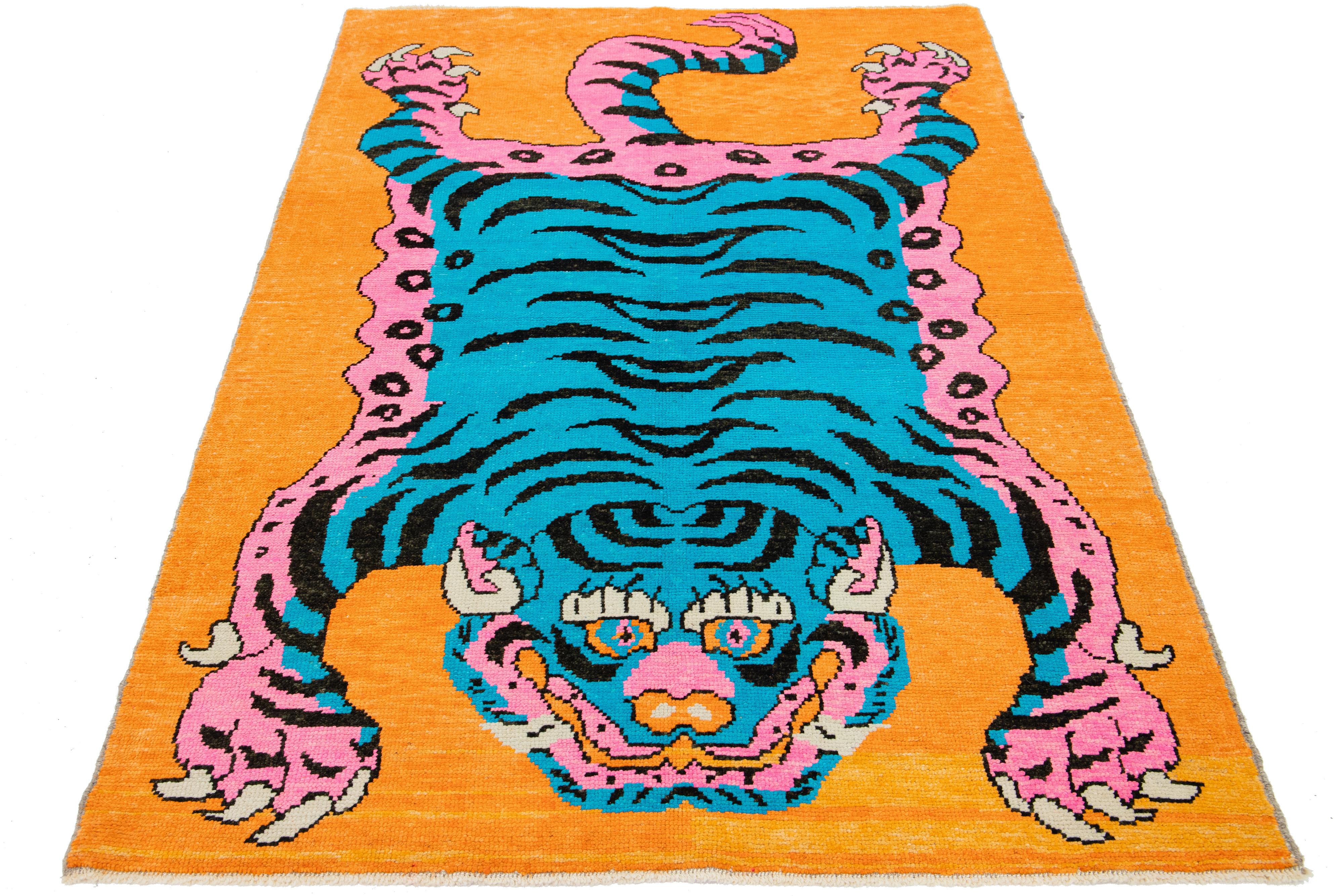 Il s'agit d'un magnifique tapis en laine Art déco turc fait à la main, avec un champ orange et des accents bleus, roses et violets dans un magnifique motif pictural de tigre. 

Ce tapis mesure 5'4