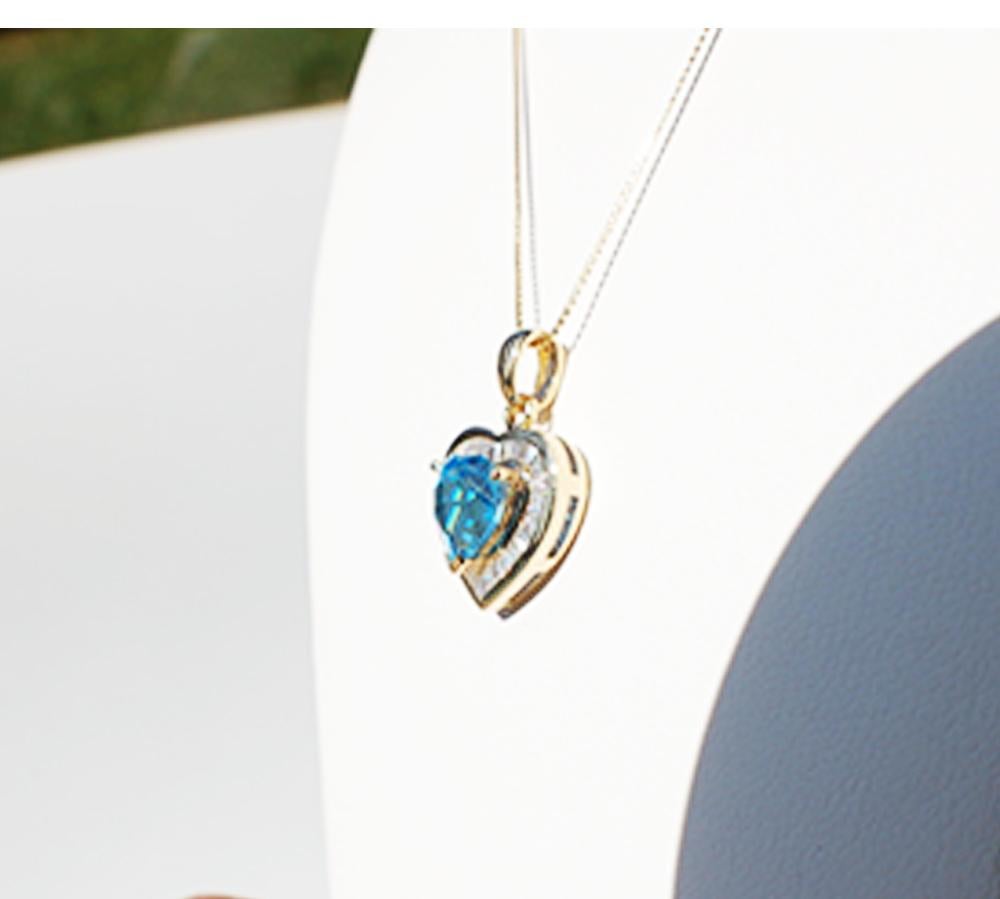 Swiss Blue Colored Topaz Pendant is Beautifully Featured in this Baguette Diamond Heart with Chain 
 This dynamic pendant is set in 14 karat yellow gold and is .60 inches in diameter, not counting the extended, chain bail 
 The heart topaz measures
