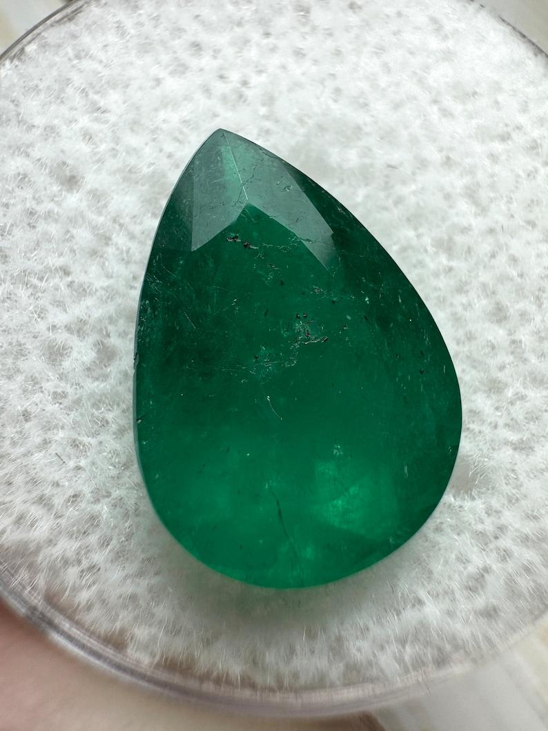 A. Stone: Smeraldo
Peso: 5,0 carati
Forma: Taglio a pera
Chiarezza: Semi-trasparente
Lucentezza: Molto buono-buono
Colore: Verde scuro
Misure: 14,53 mm x 10,31 mm x 6,61 mm
Origine geografica: Colombia
Trattamento: Naturale, oliatura

Commenti: A