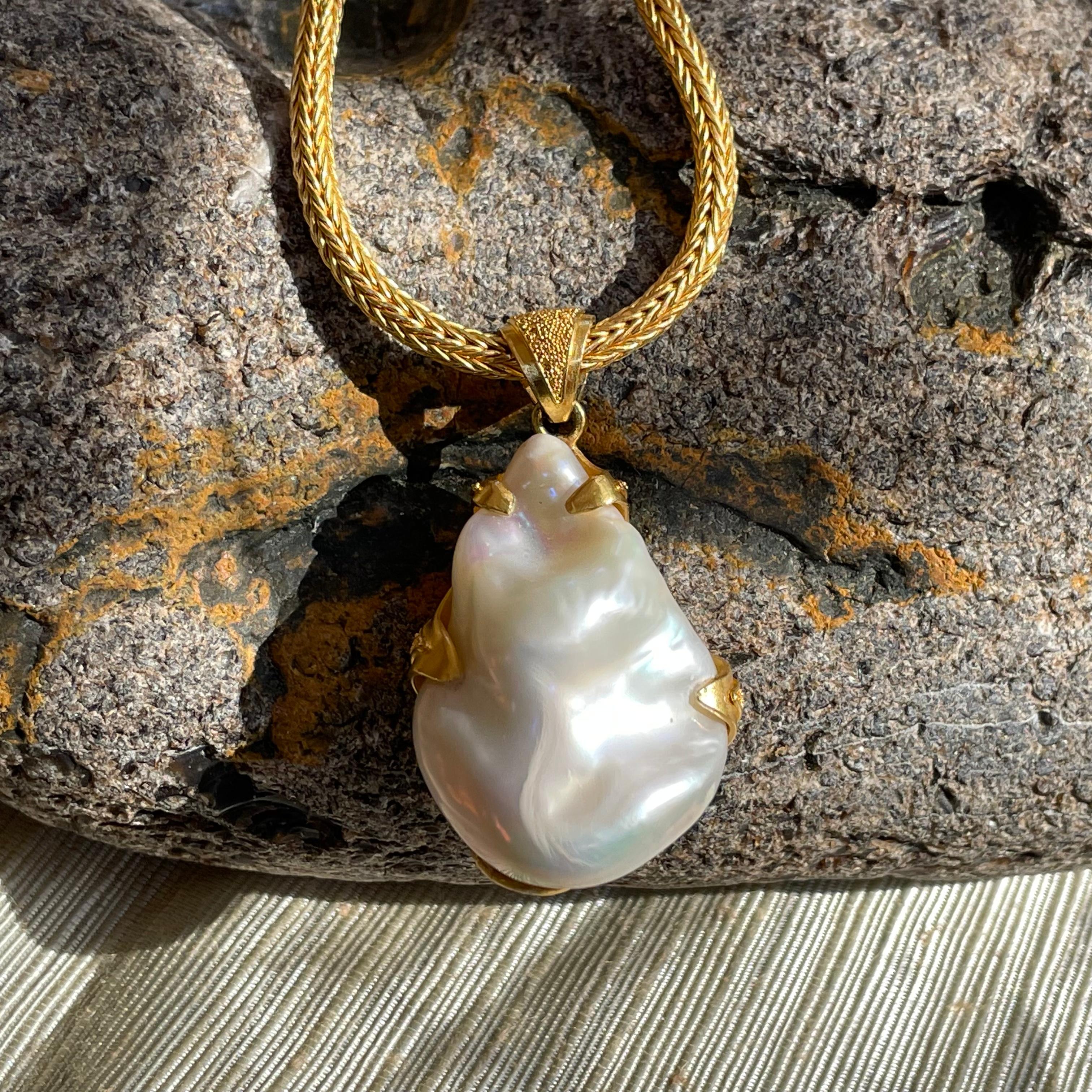 A high luster, large, 22 x 32 mm irregular freshwater pearl is held in 22 karat gold embrace with granulated accents in this distinctive Steven Battelle pendant.  The woven chain shown is not included but can be ordered additionally.